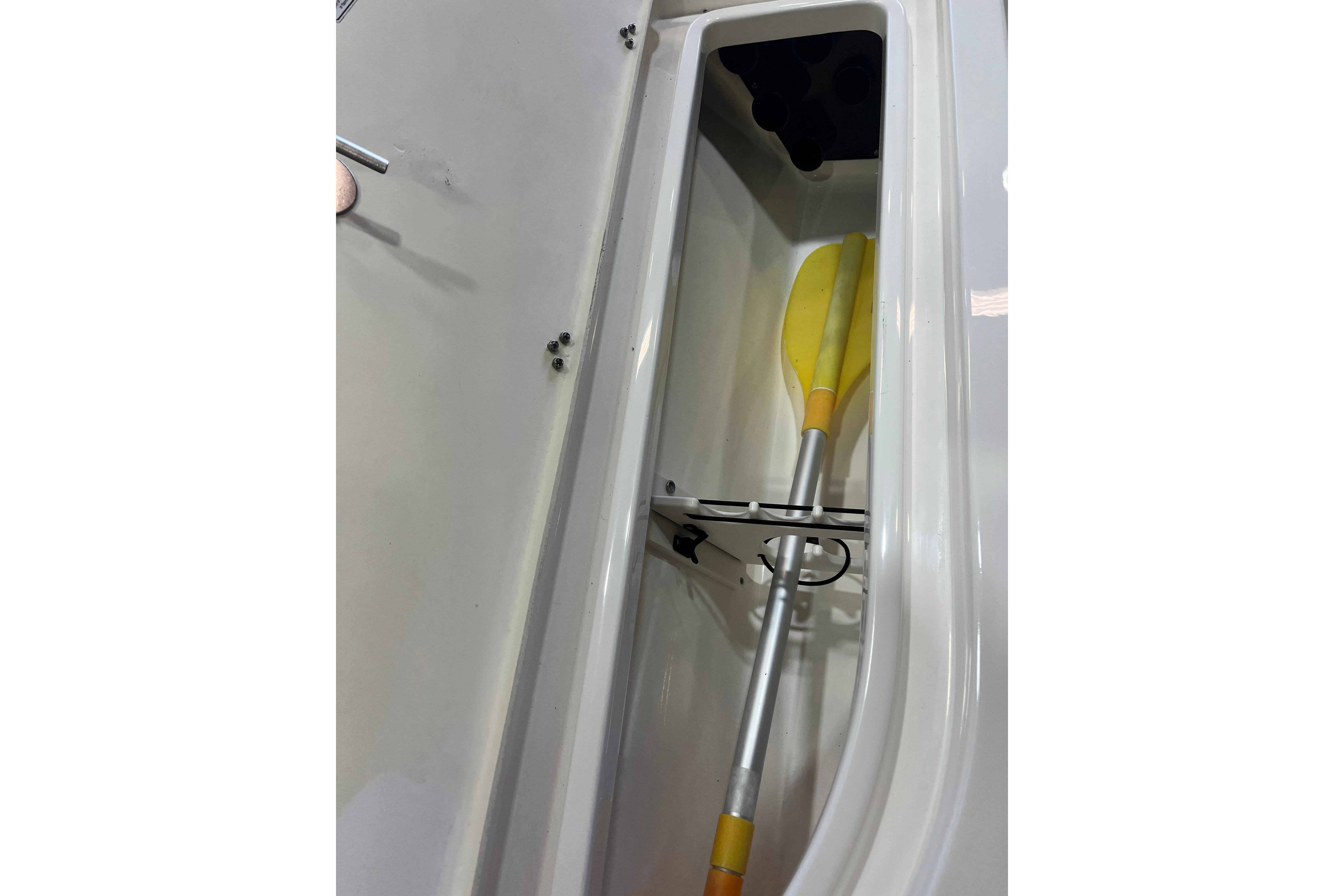 Storage compartment with yellow paddle in 2023 NauticStar 227 XTS boat.