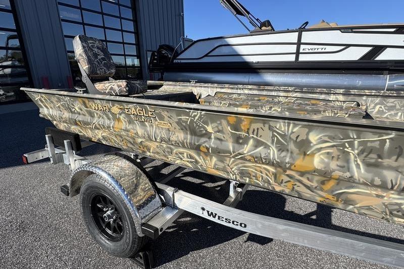 2026 War Eagle 648LDV camo boat on Wesco trailer, parked outdoors.