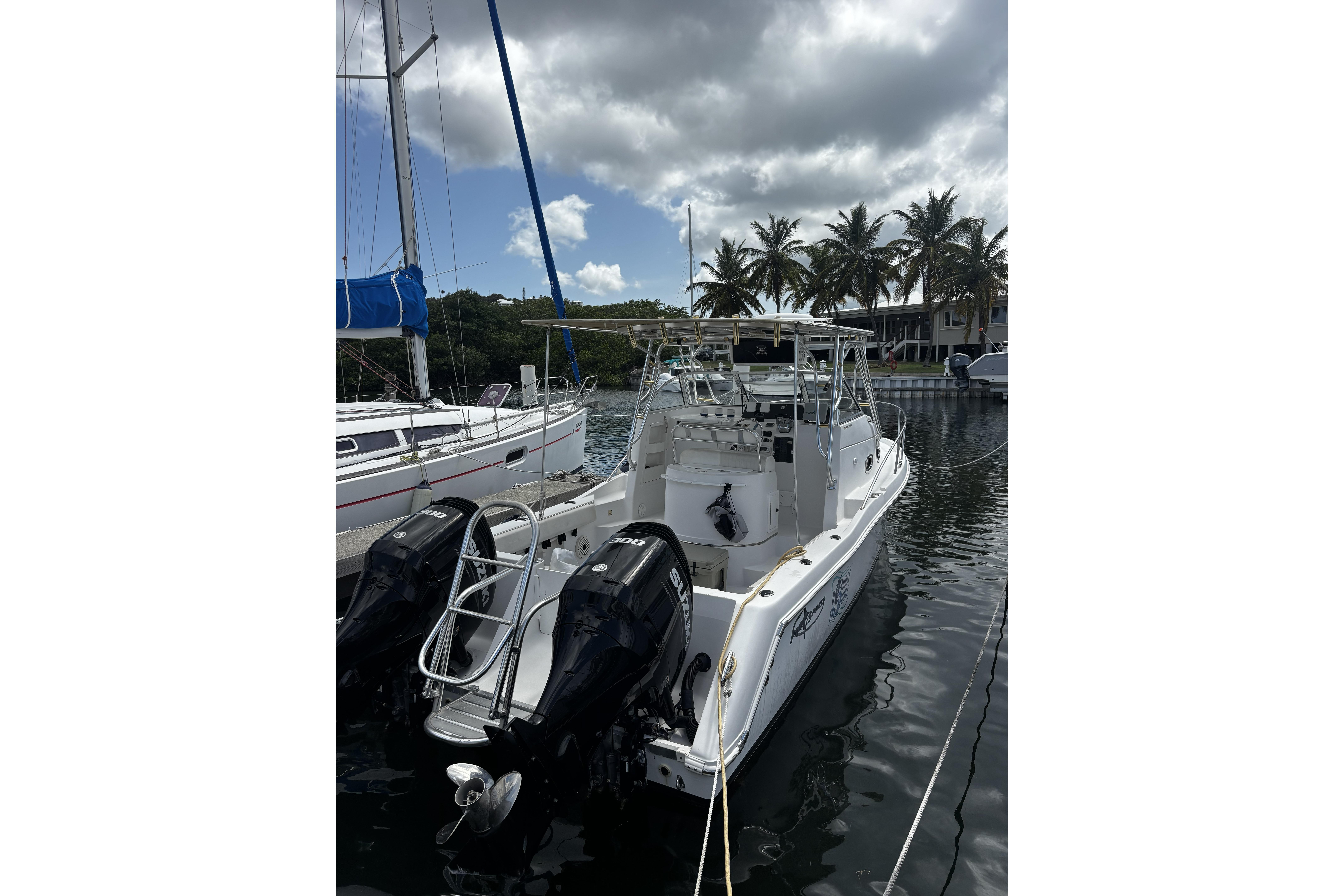 2005 Prosports 2860 KATWA boat docked, featuring dual outboard motors, under cloudy sky.