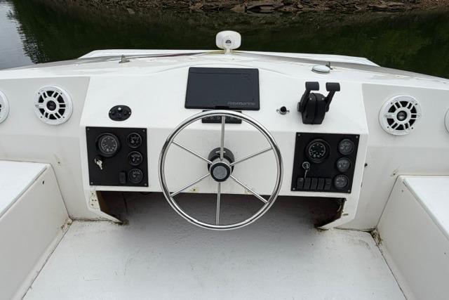 Cockpit of a 1997 Stardust Houseboat 18x83, featuring steering wheel and control panel.