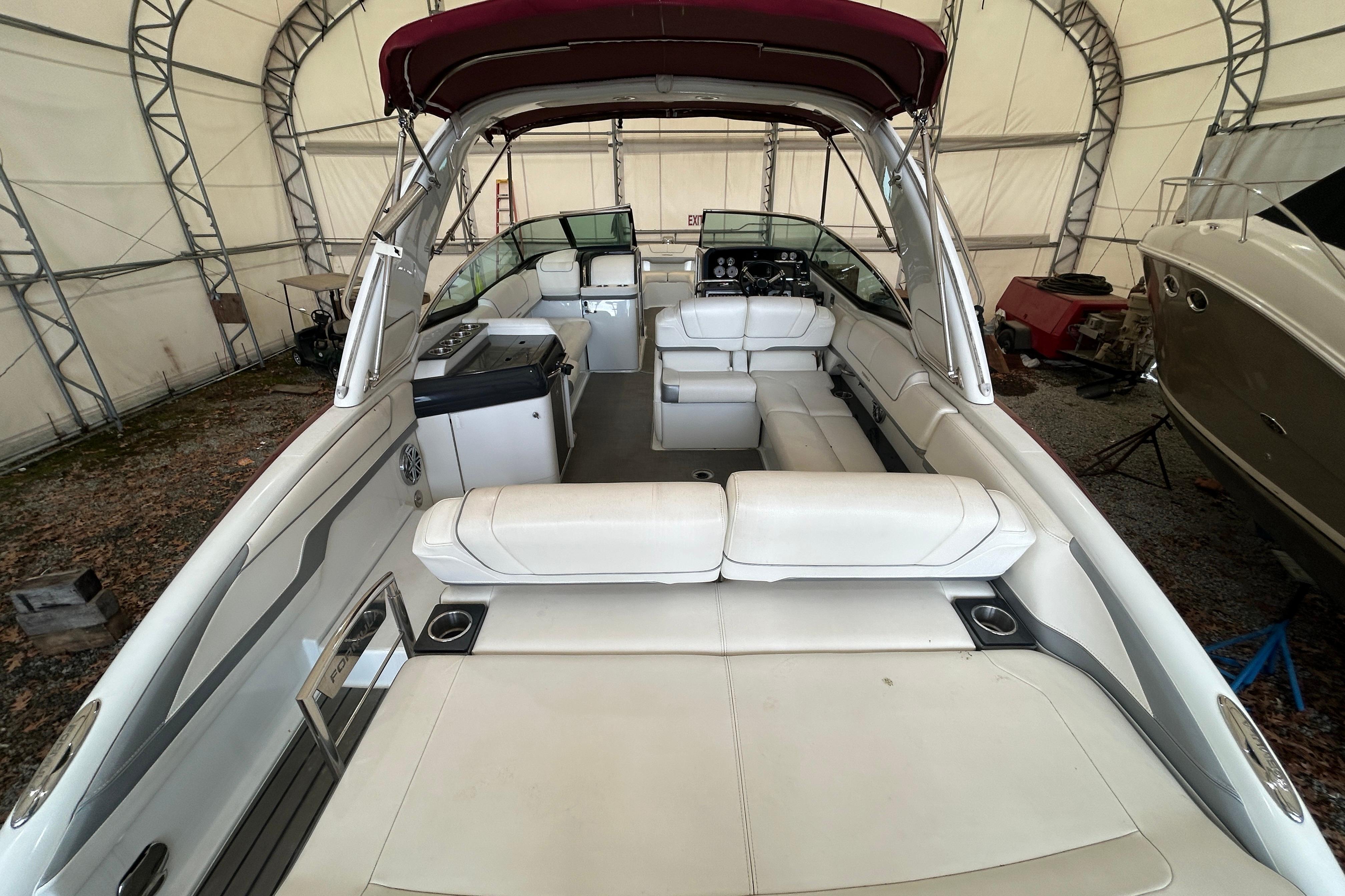 2015 Formula 310 Bowrider with spacious white seating and maroon canopy in storage.