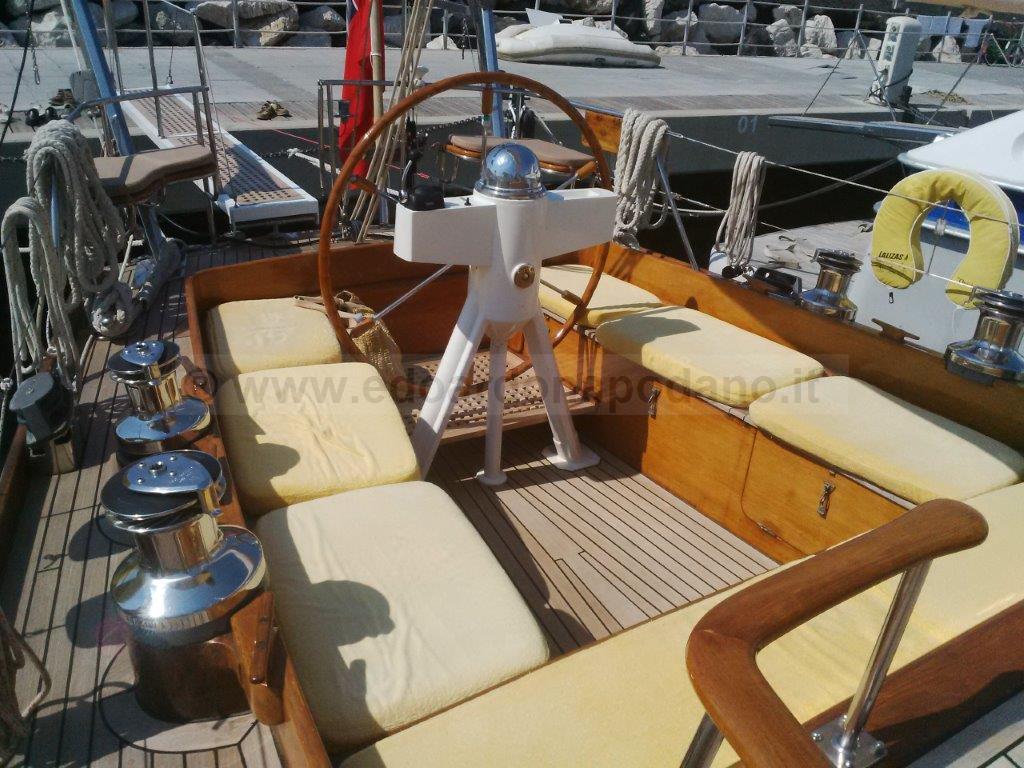 1976 Sangermani Ketch yacht deck with wooden helm and cushioned seating.