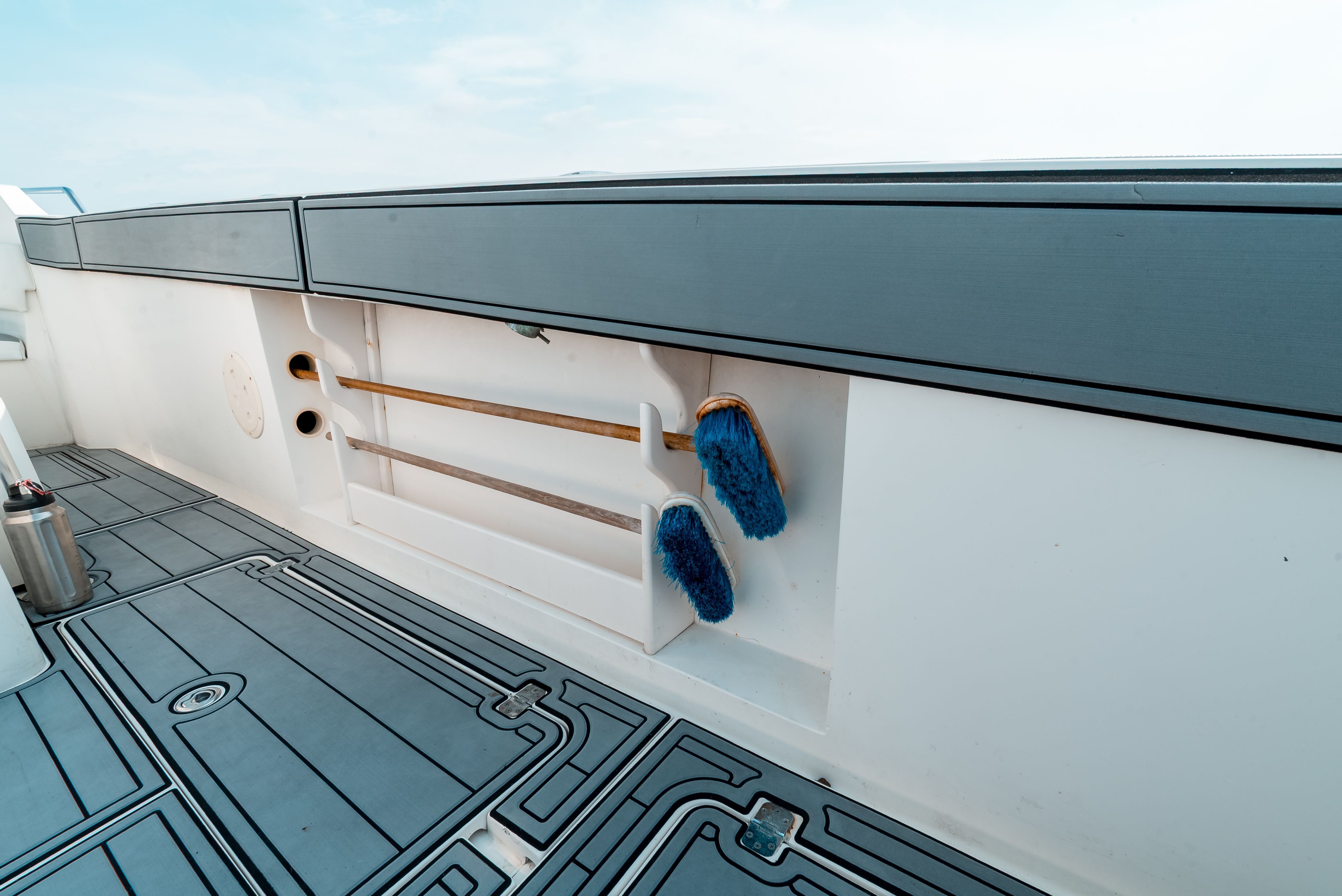 The image shows a boat deck with blue brushes and rods mounted on the wall.