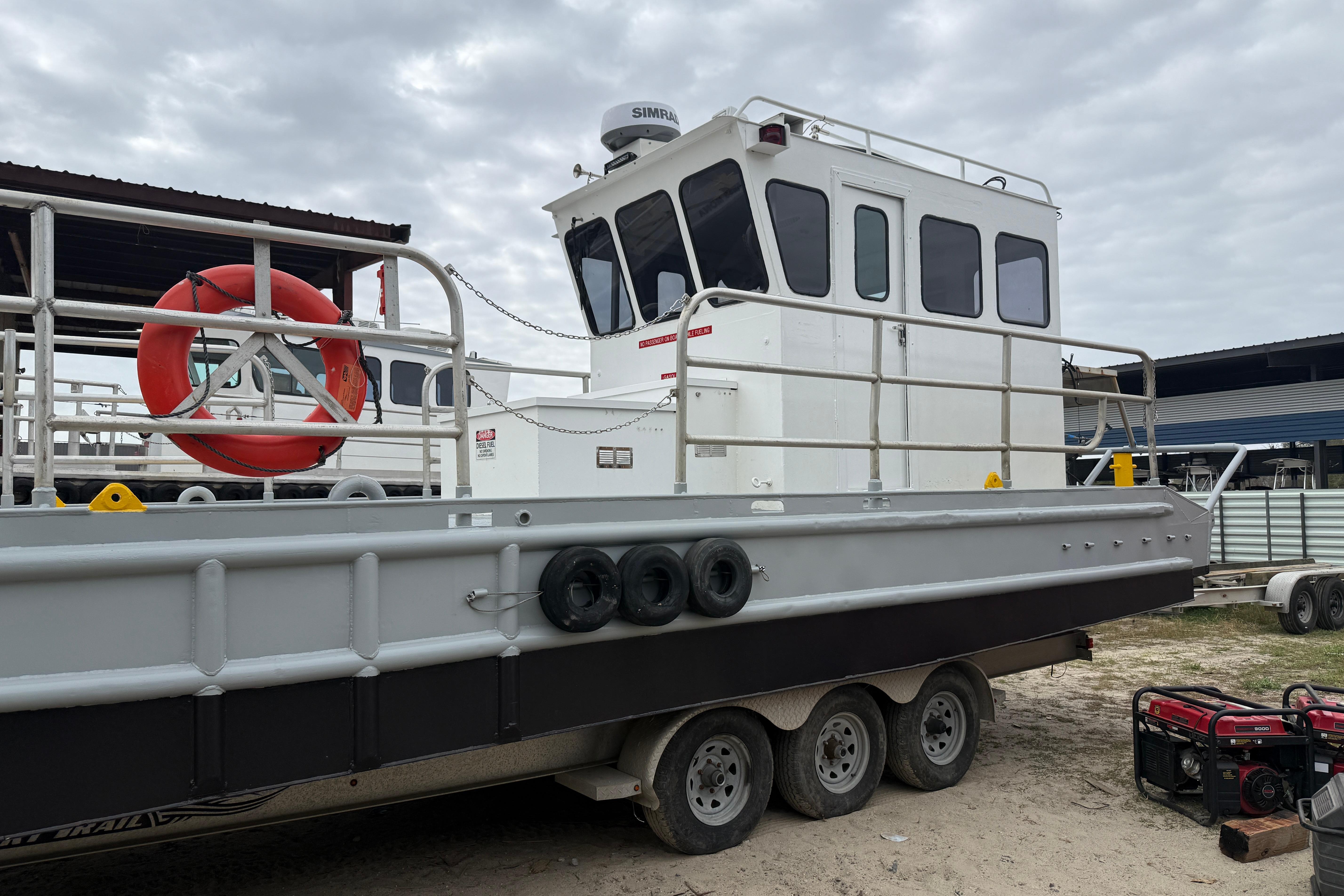 Custom Aluminum Work Boat 34x10, 2010 model, docked with safety equipment and overcast sky.