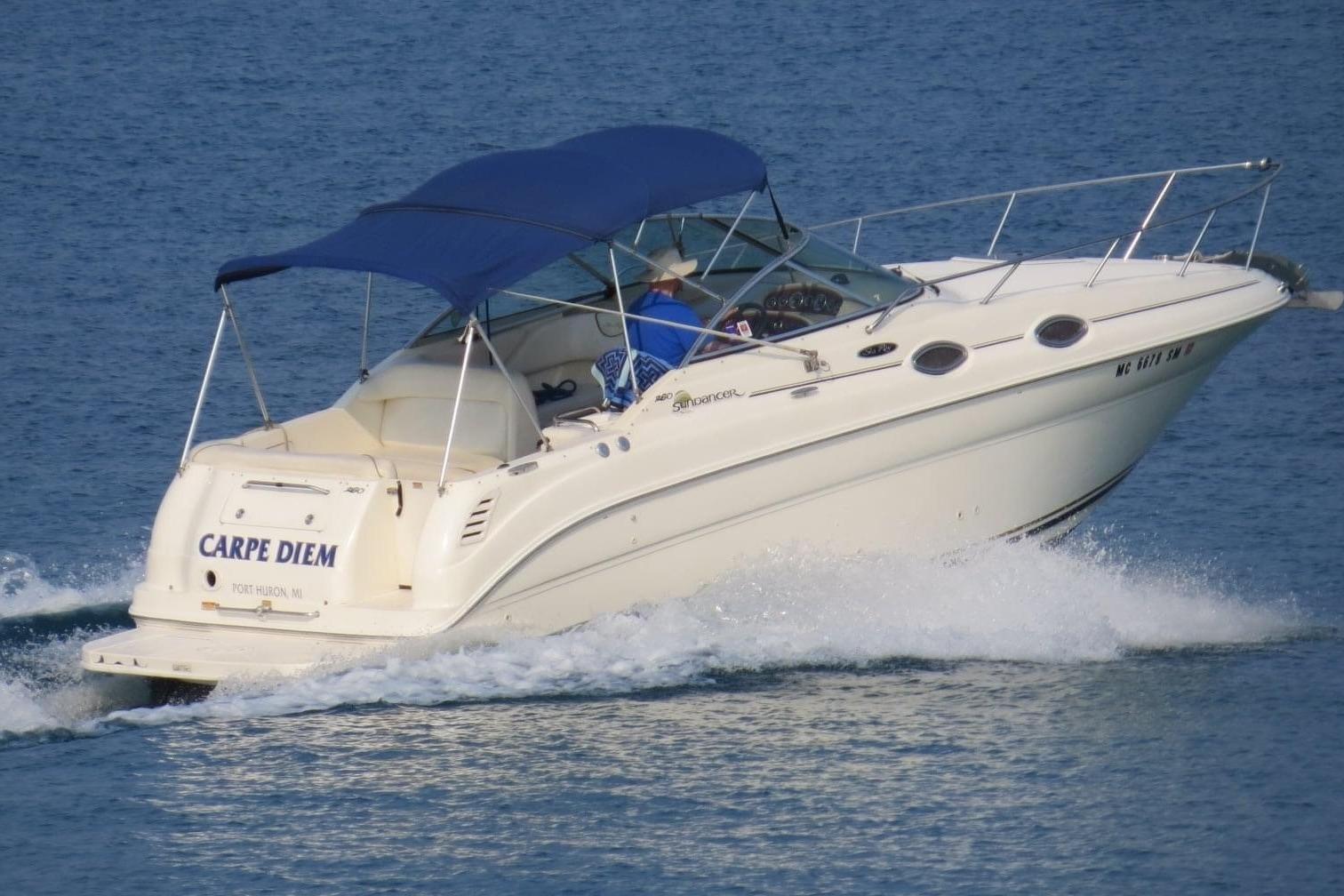 2003 Sea Ray 260 Sundancer boat cruising on water with blue canopy.