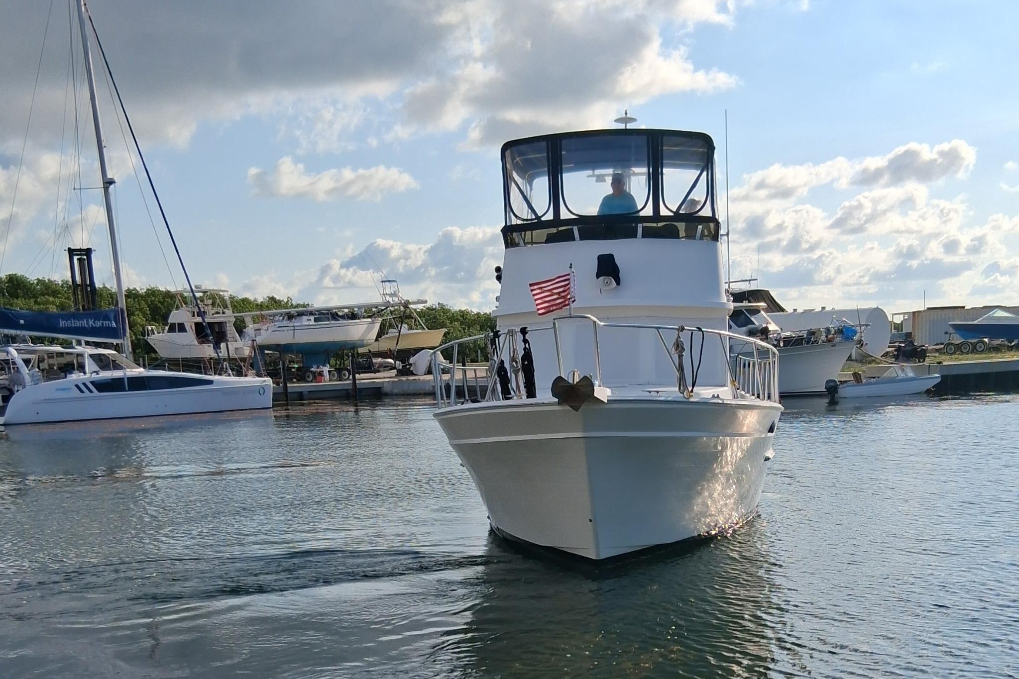 Ricker 42 Classic yacht from 2000 cruising in a marina under a partly cloudy sky.