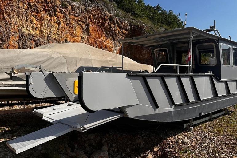 ALUTEH LC 853 boat, 2018 model, docked near rocky terrain with covered vessel nearby.