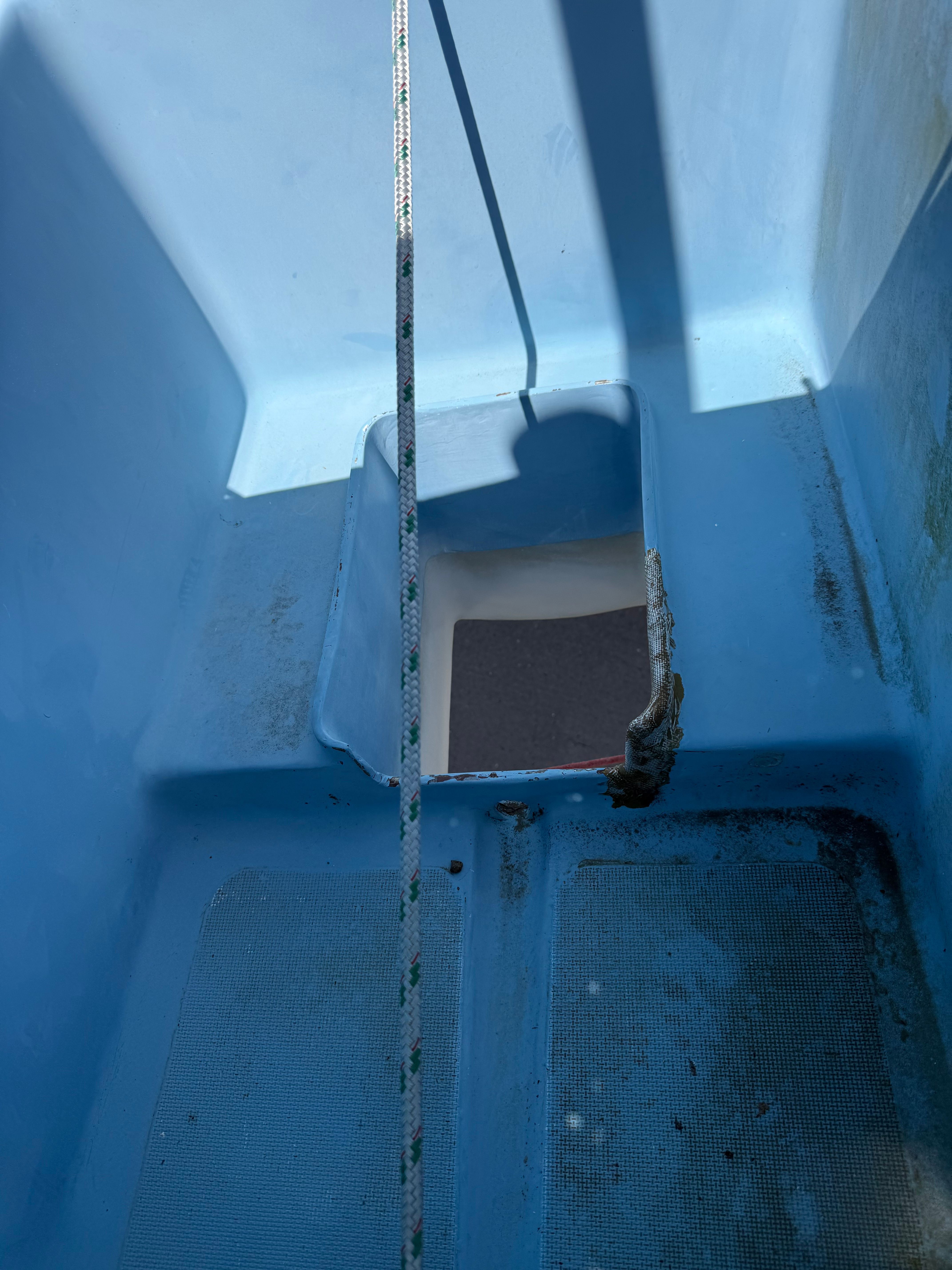 View into the blue cockpit of a 1965 CAL 20 sailboat with rope and shadows.