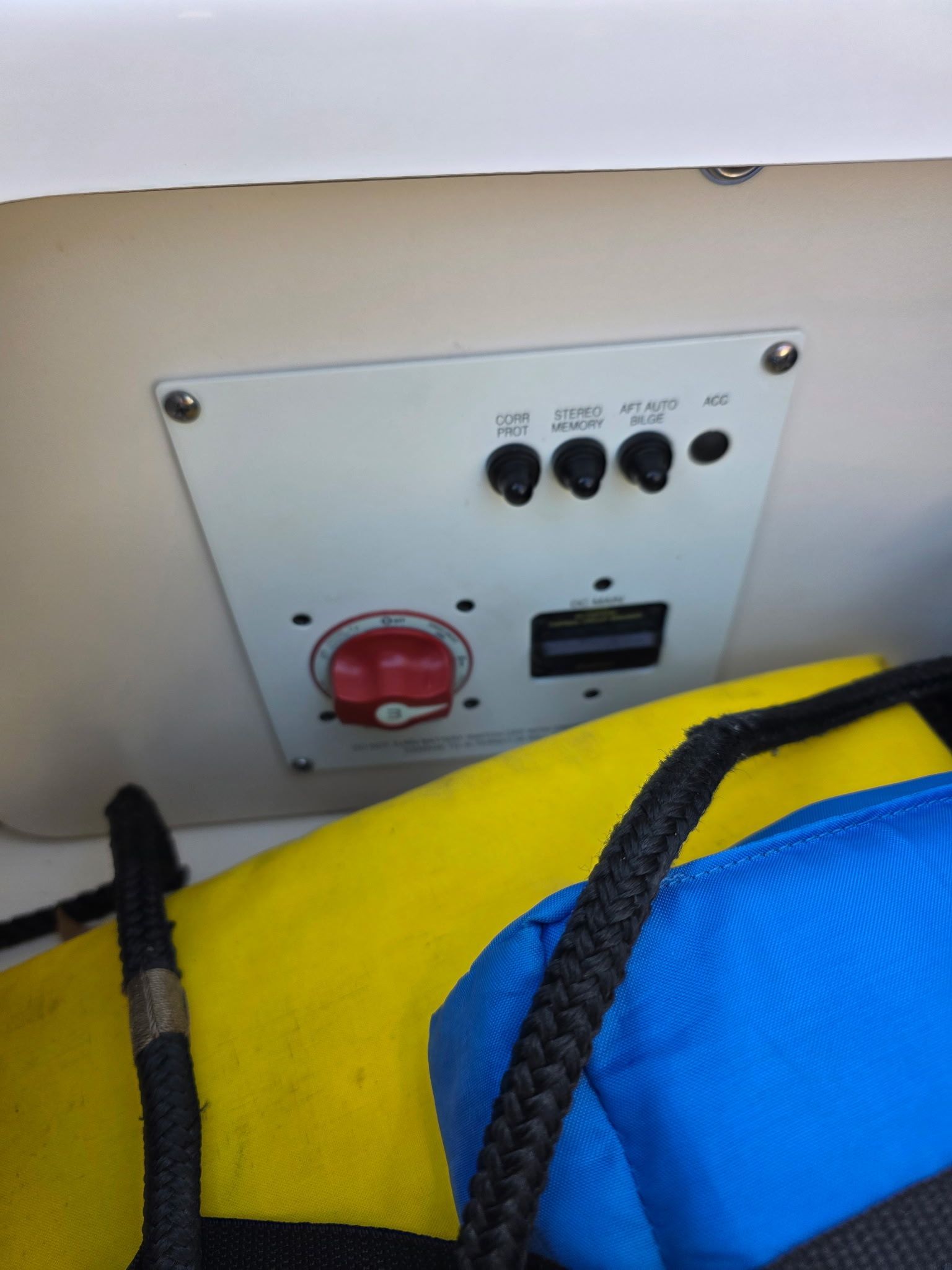 A control panel with switches and a red rotary knob, partially obscured by a yellow bag.