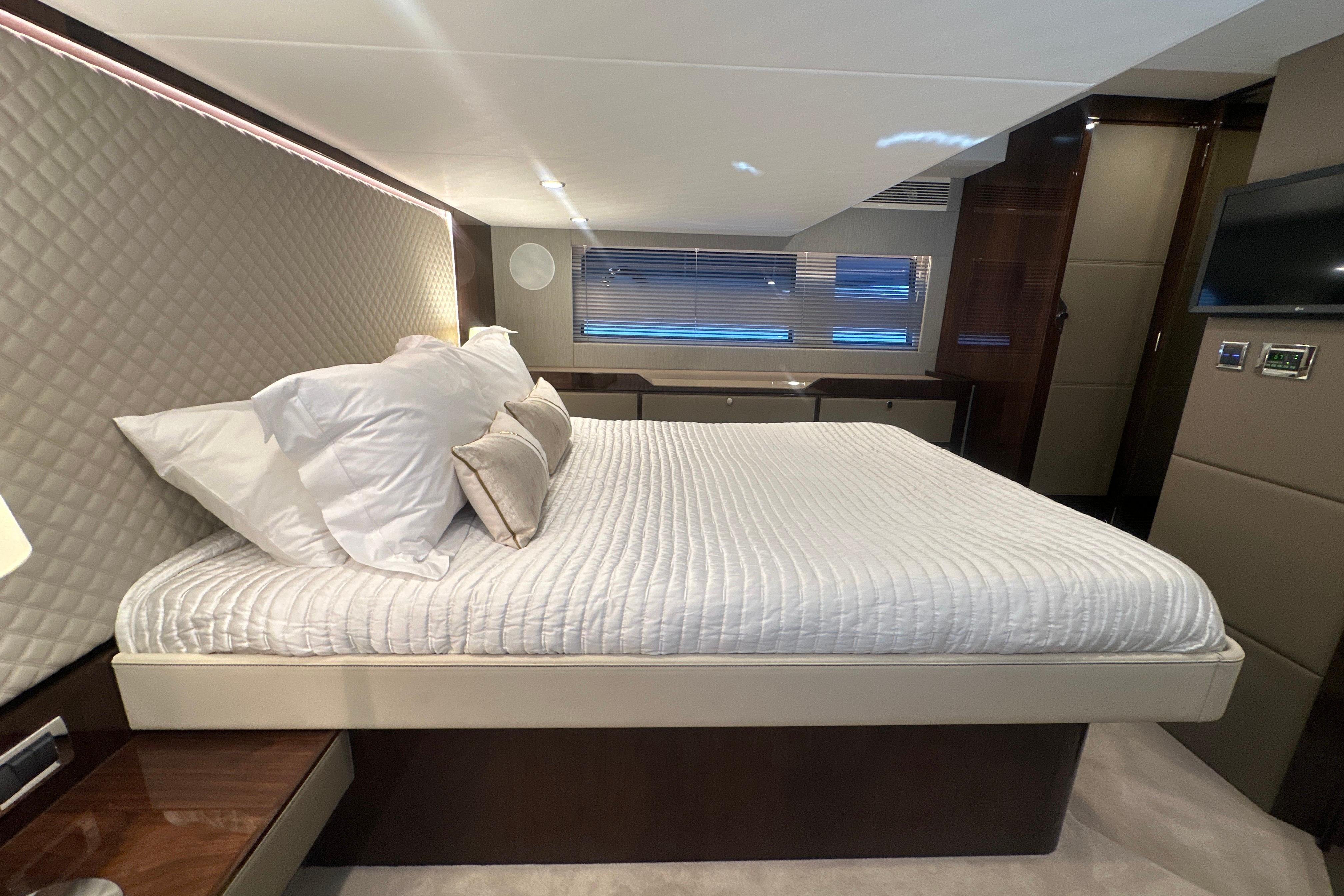Luxurious bedroom interior of 2024 Fairline Squadron 50 yacht with elegant bedding.