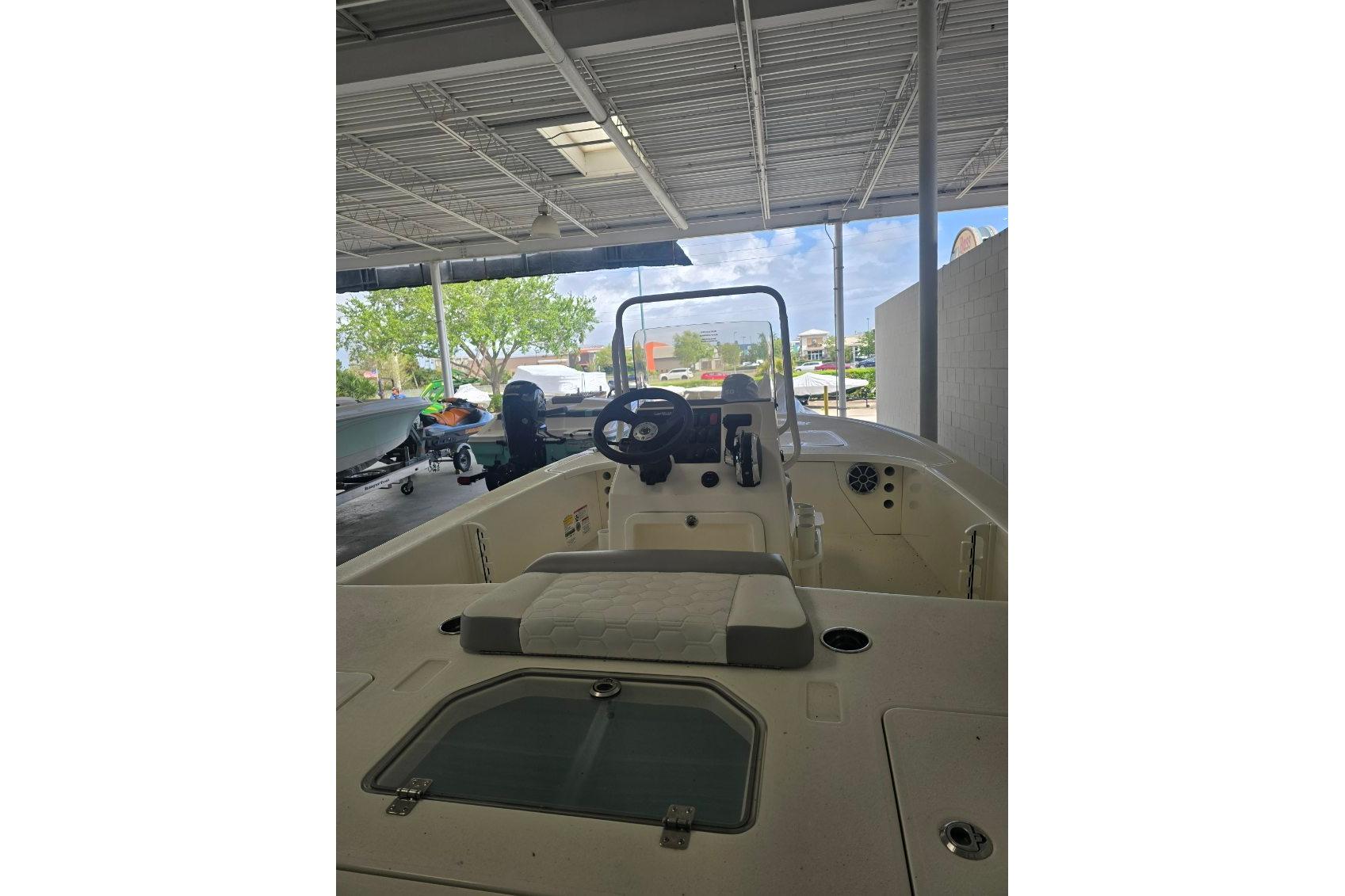 2026 Mako 18 Pro Skiff boat interior under a covered area, showcasing steering and seating.
