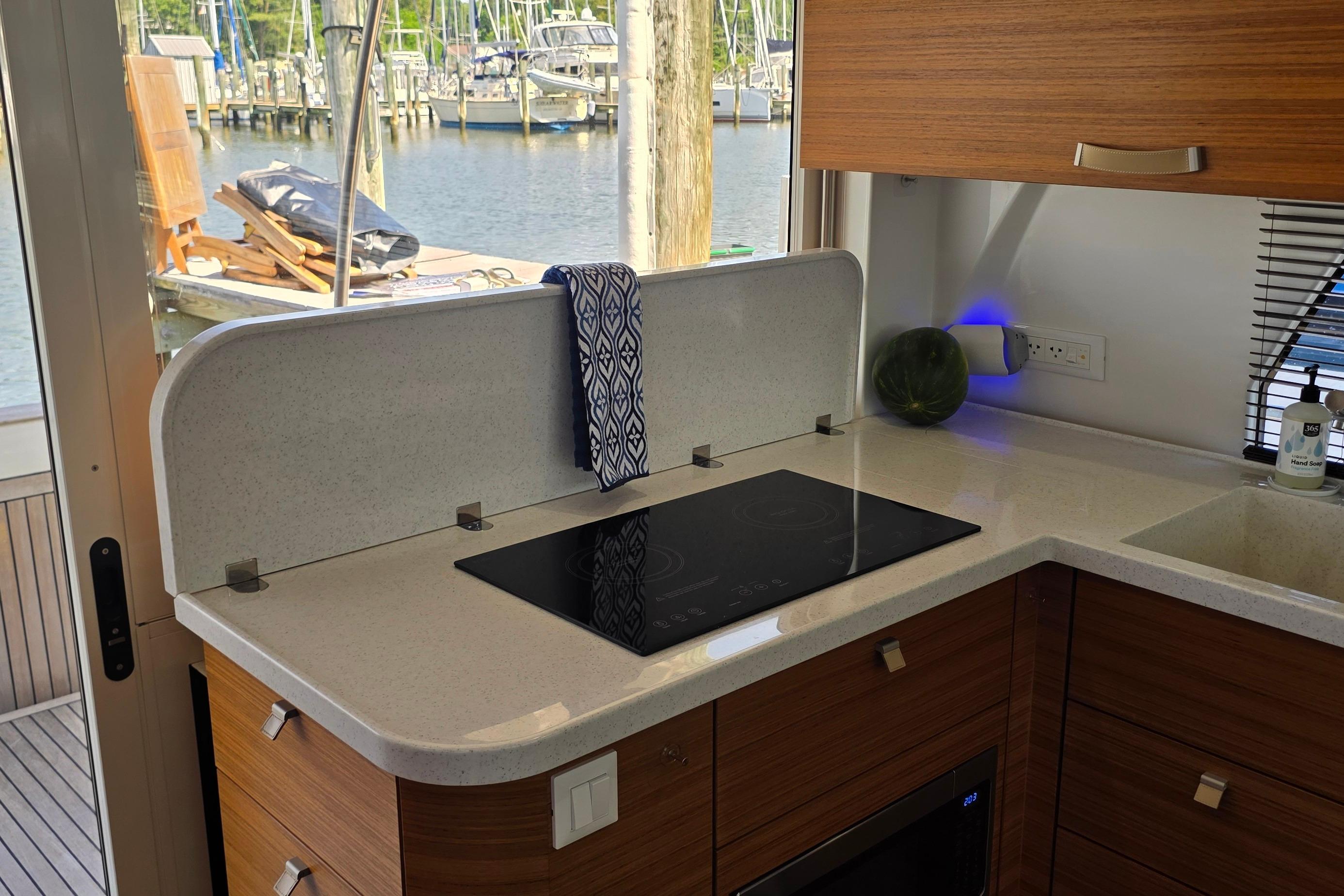 Modern kitchen in 2023 Greenline 40 yacht with sleek countertop and induction cooktop.