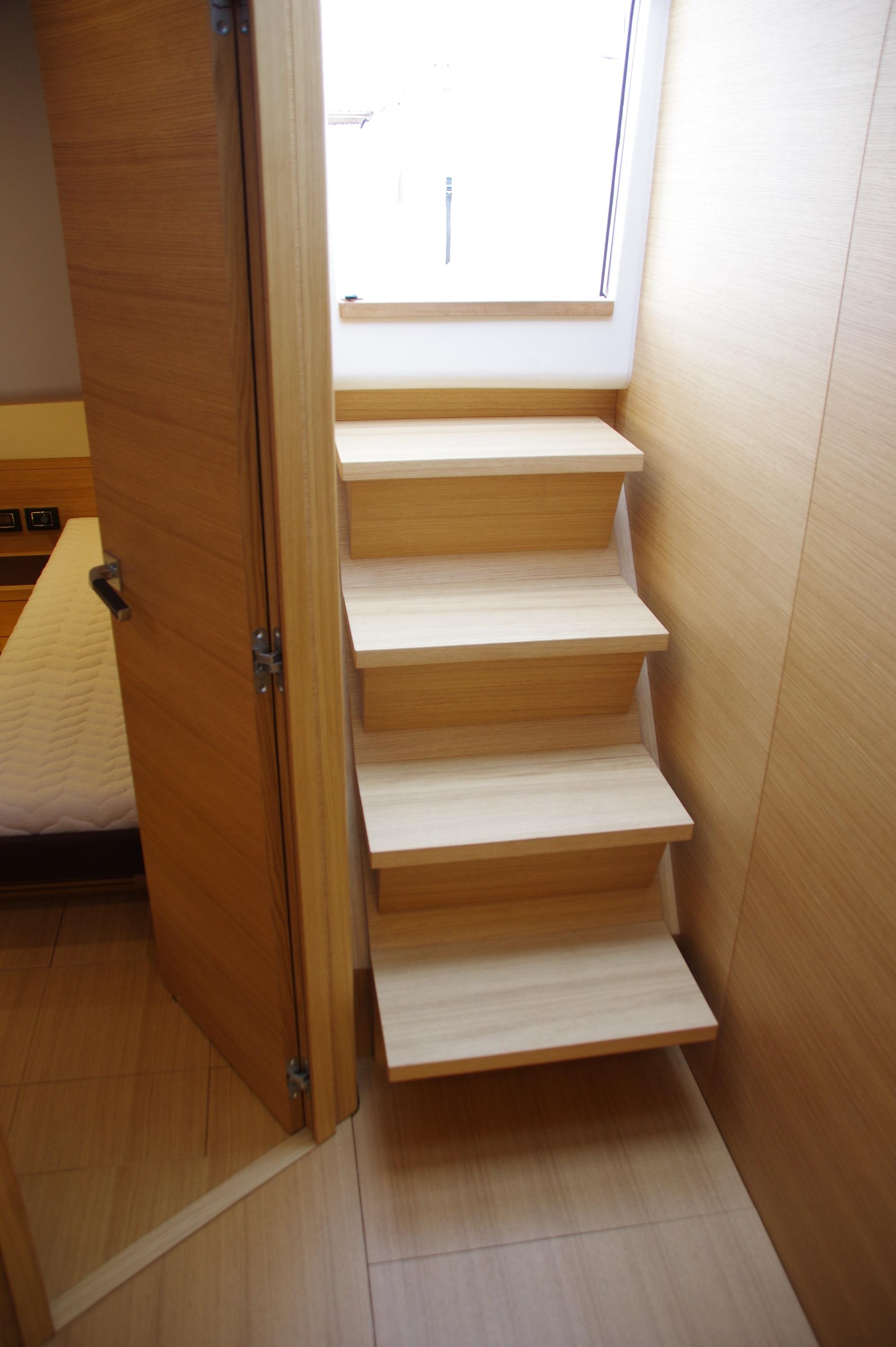 Interior of 2025 Pardo Yachts 50, featuring wooden stairs and a cabin door.