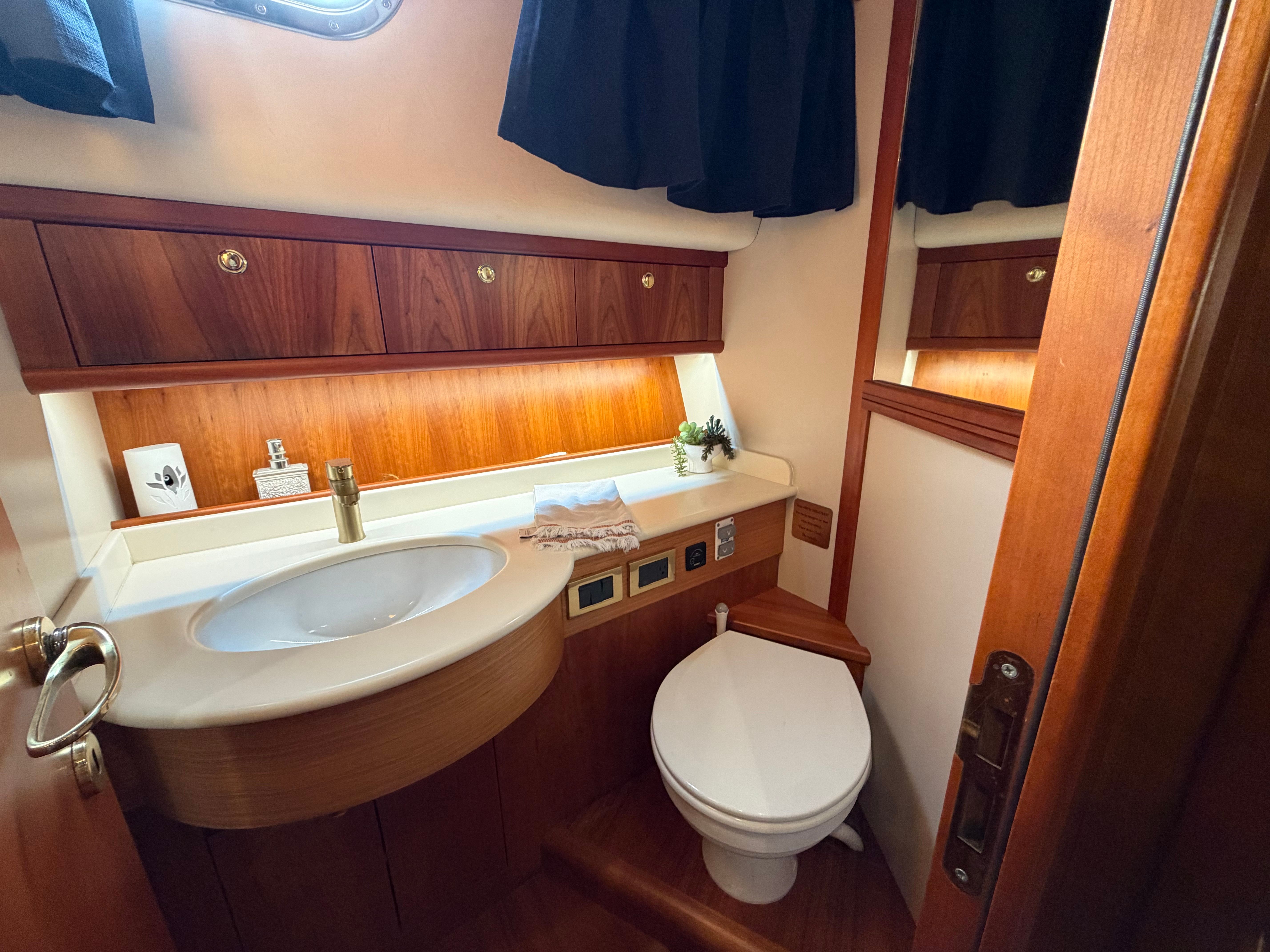 The image shows an elegant boat bathroom with wood paneling and modern fixtures.