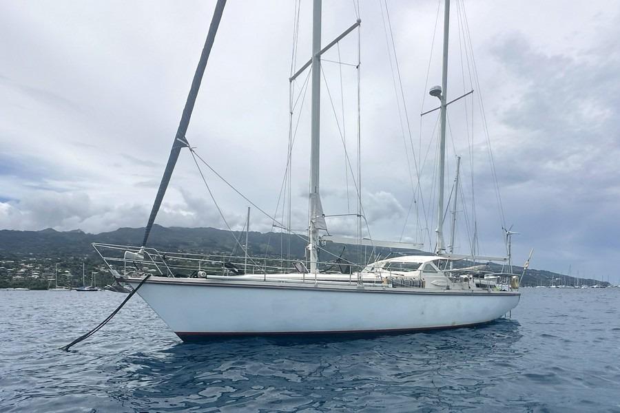 Sailing yacht Amel Super Maramu 1993 anchored in calm waters with cloudy sky.