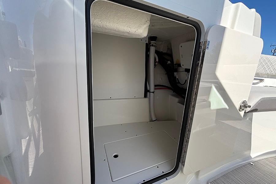 2027 Sea Ray SDX 230 Outboard storage compartment, open door, white interior.