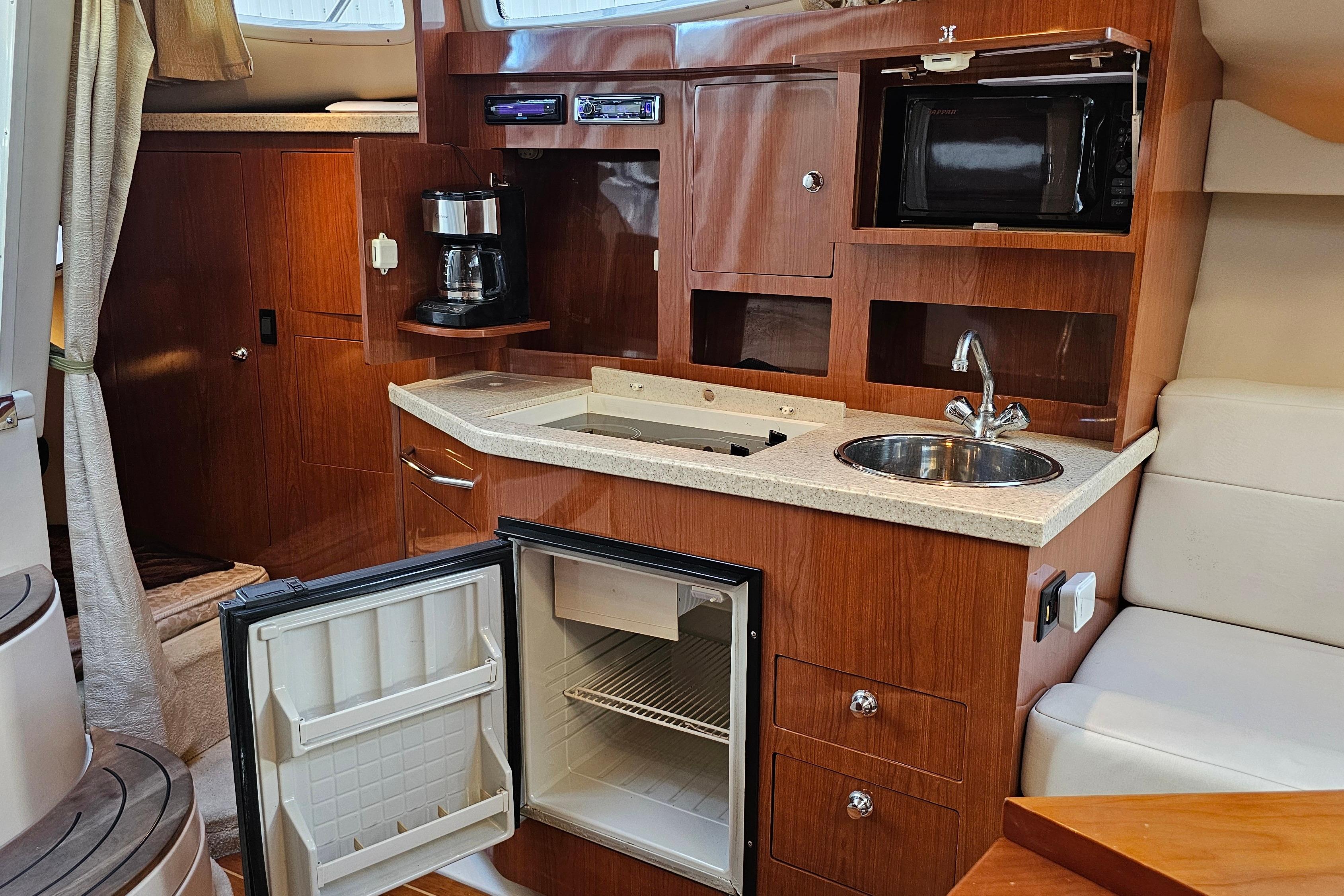 2005 Regal 3060 Window Express yacht interior with kitchenette, featuring sink, fridge, and microwave.