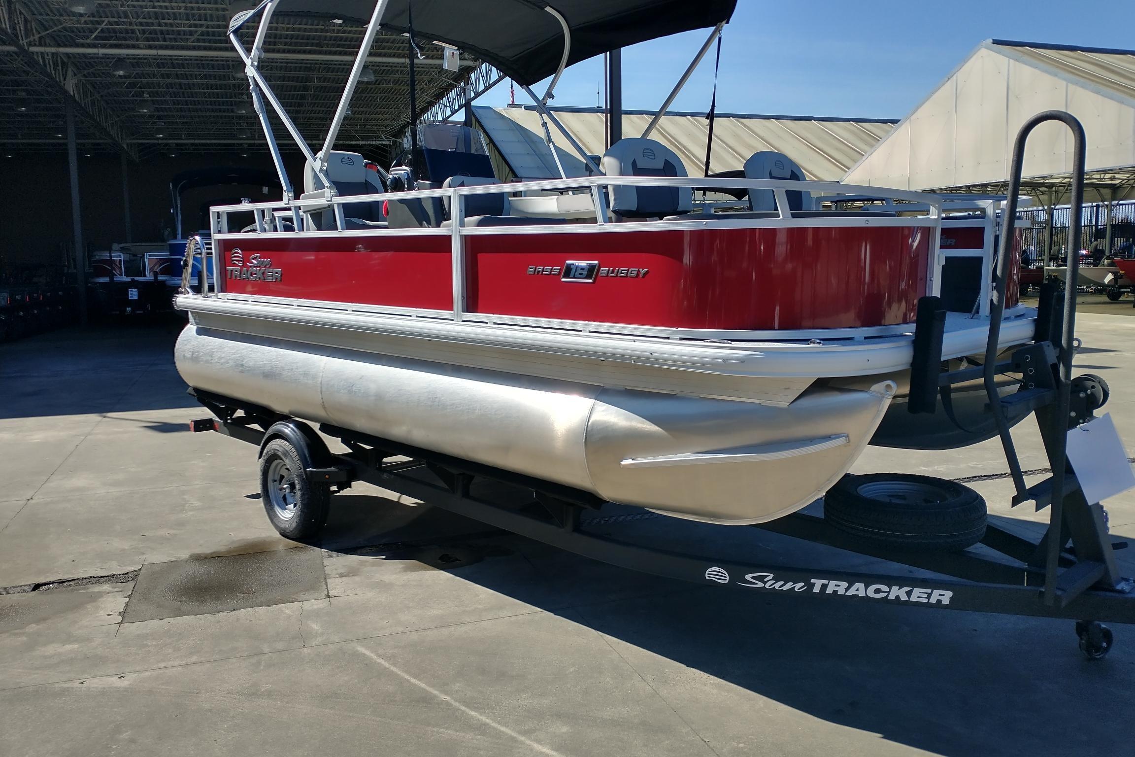 2026 Sun Tracker Bass Buggy 18 DLX pontoon boat on trailer, red and silver design.