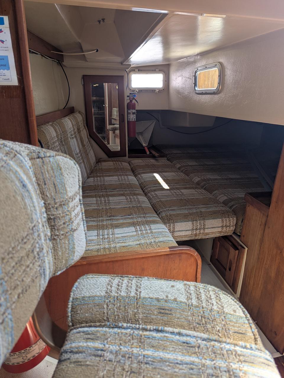 Interior of a 1985 Catalina 36 sailboat with plaid seating and wooden accents.