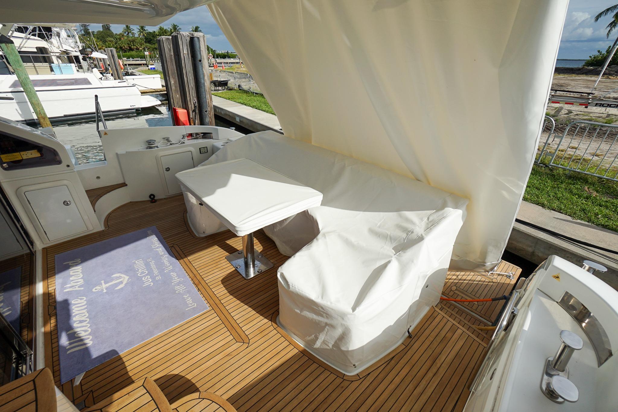 Azimut 54 Flybridge 2014 yacht deck with covered seating and table, docked at marina.