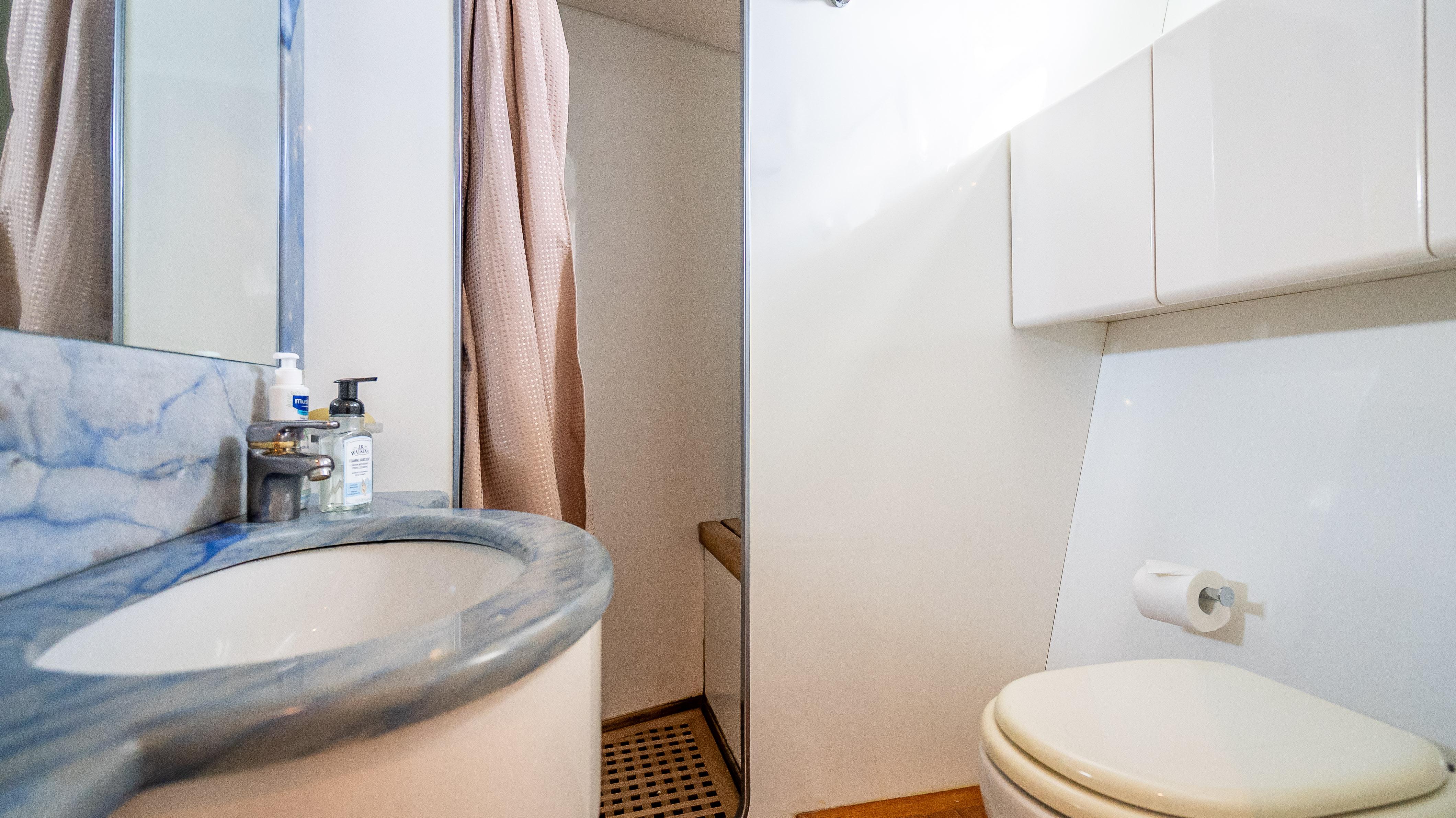Bathroom interior of a 1995 Sanlorenzo 62 yacht with marble countertop and shower.