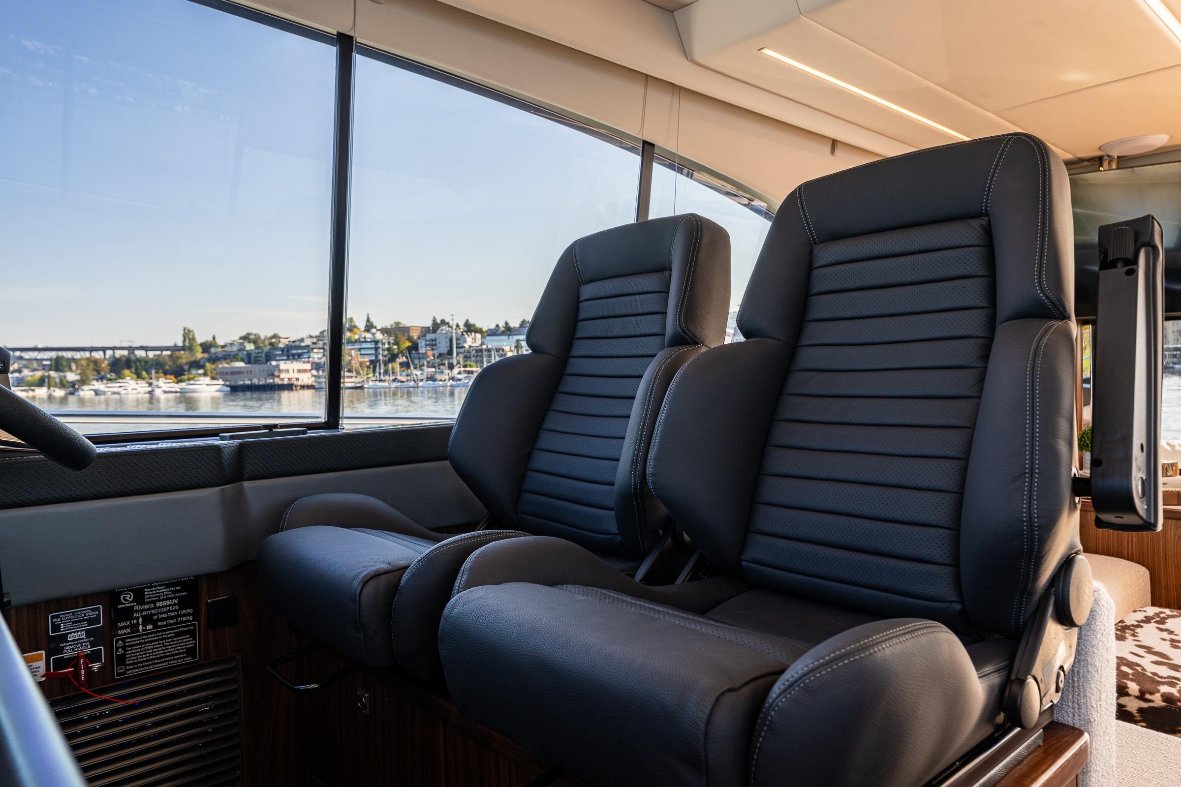 Luxurious interior seating of 2026 Riviera 505 SUV yacht with waterfront view.