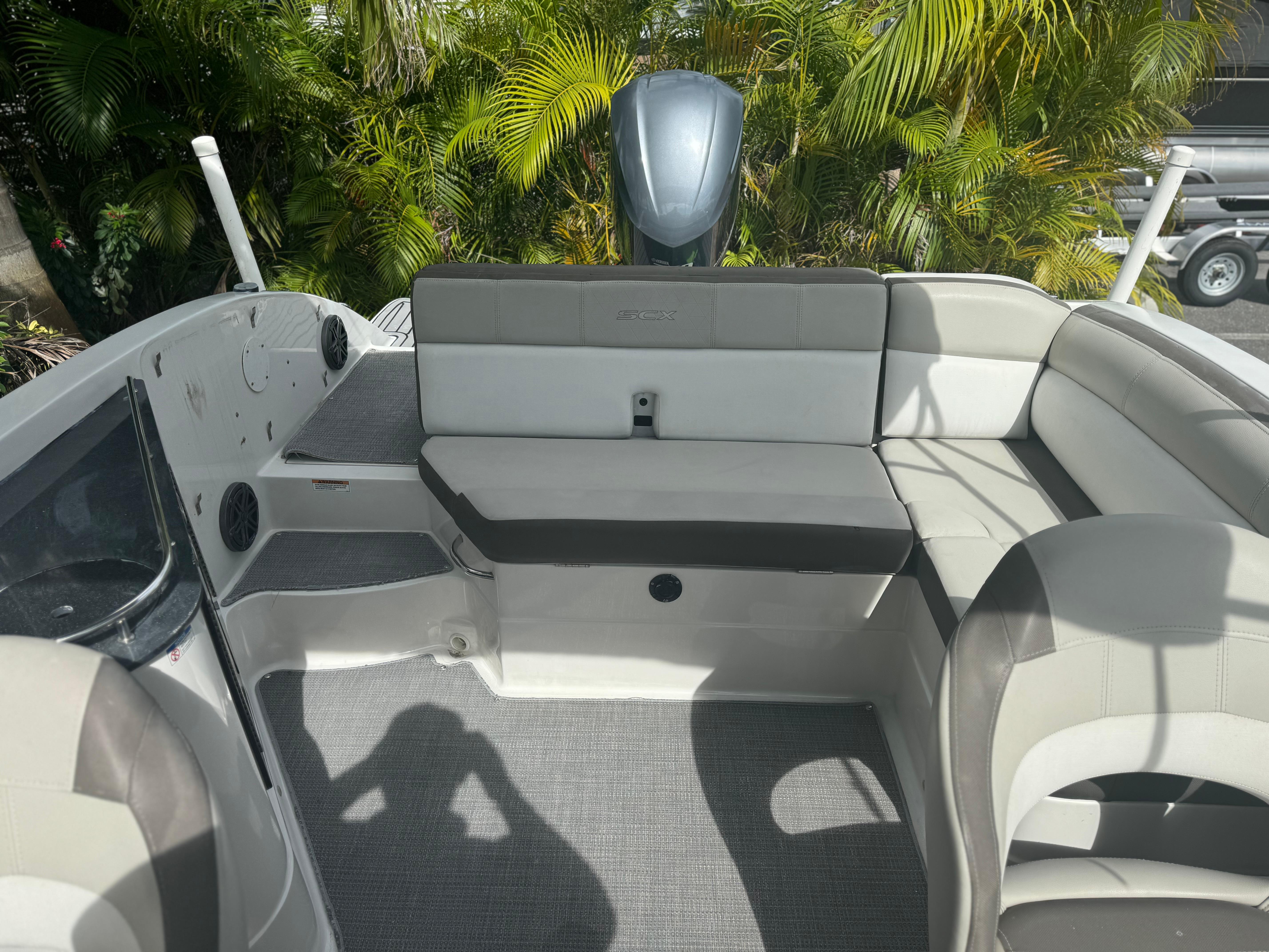 2017 Starcraft 230 OB SCX EXT boat interior with cushioned seating and lush greenery background.