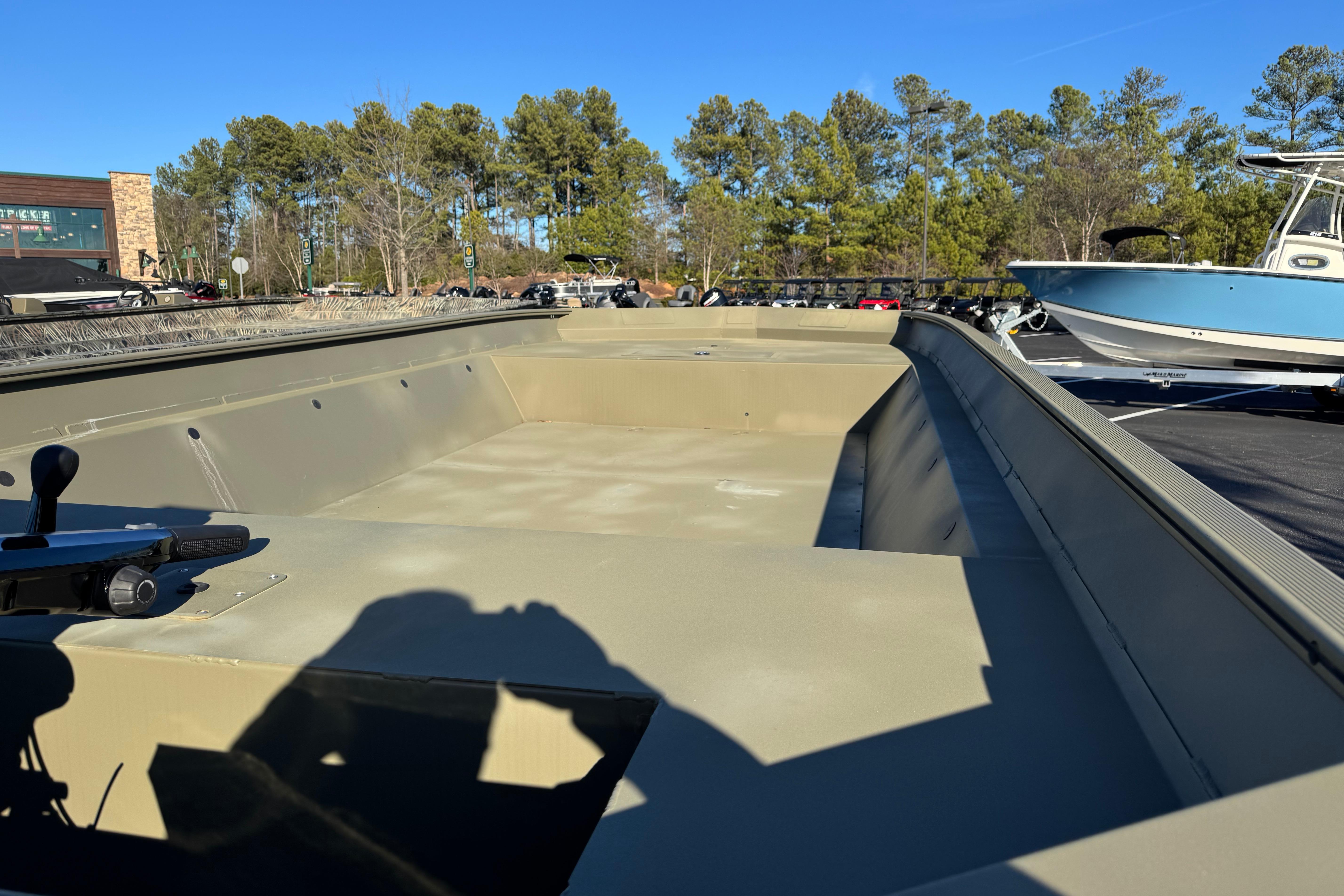 2026 Tracker Grizzly 2072 Utility boat in parking lot, surrounded by trees and other boats.
