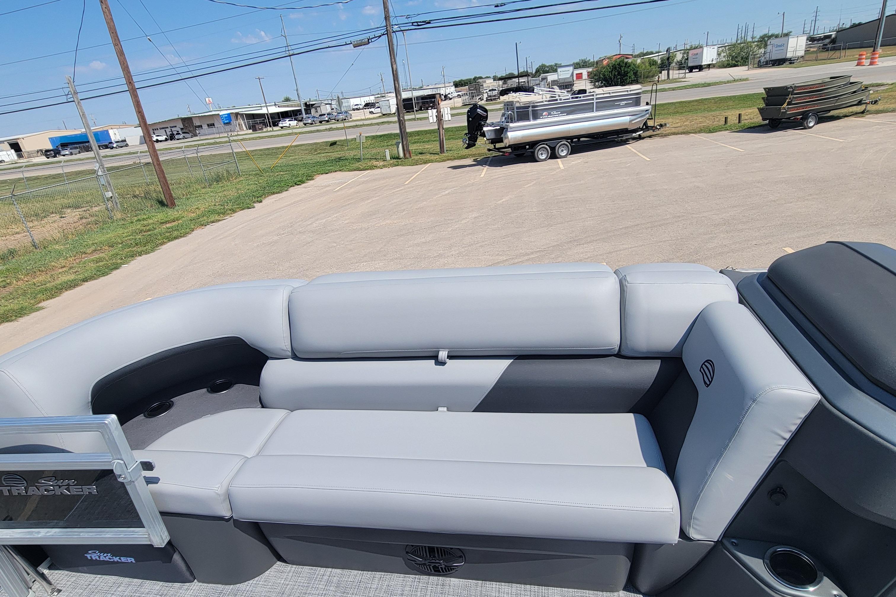2026 Sun Tracker SportFish 20 DLX pontoon boat with gray seating in a parking lot.