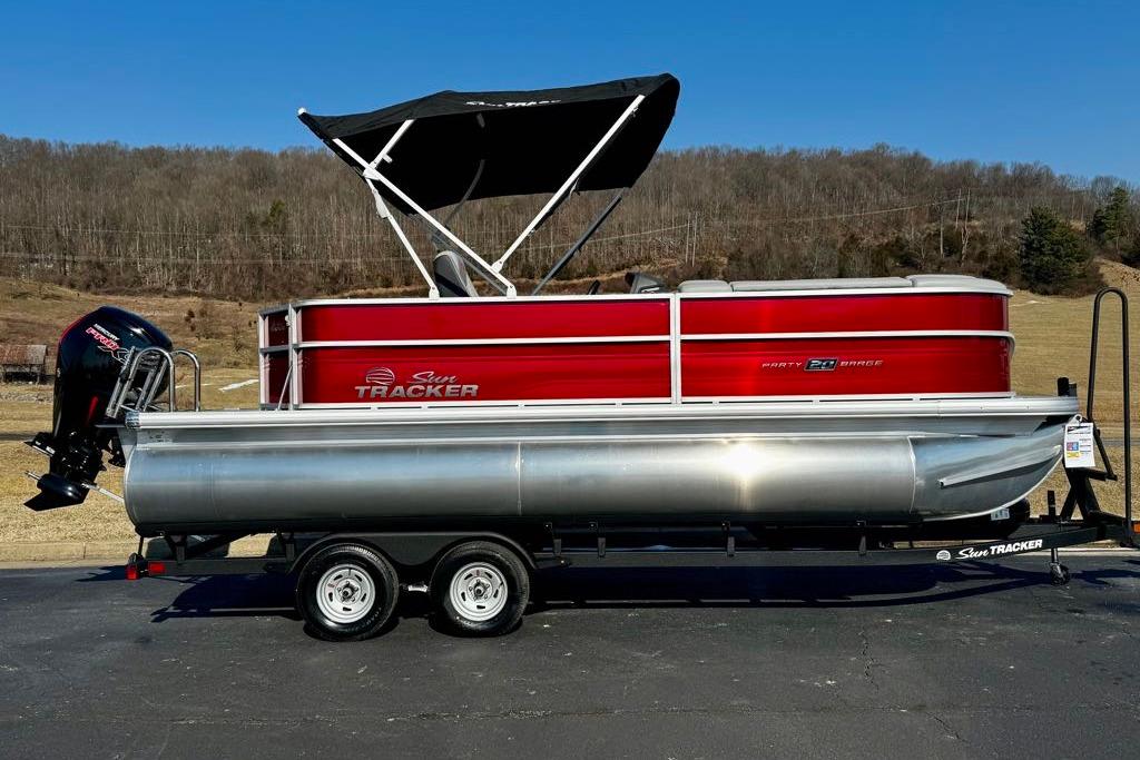 2026 Sun Tracker Party Barge 20 DLX pontoon boat on trailer, red and silver design.