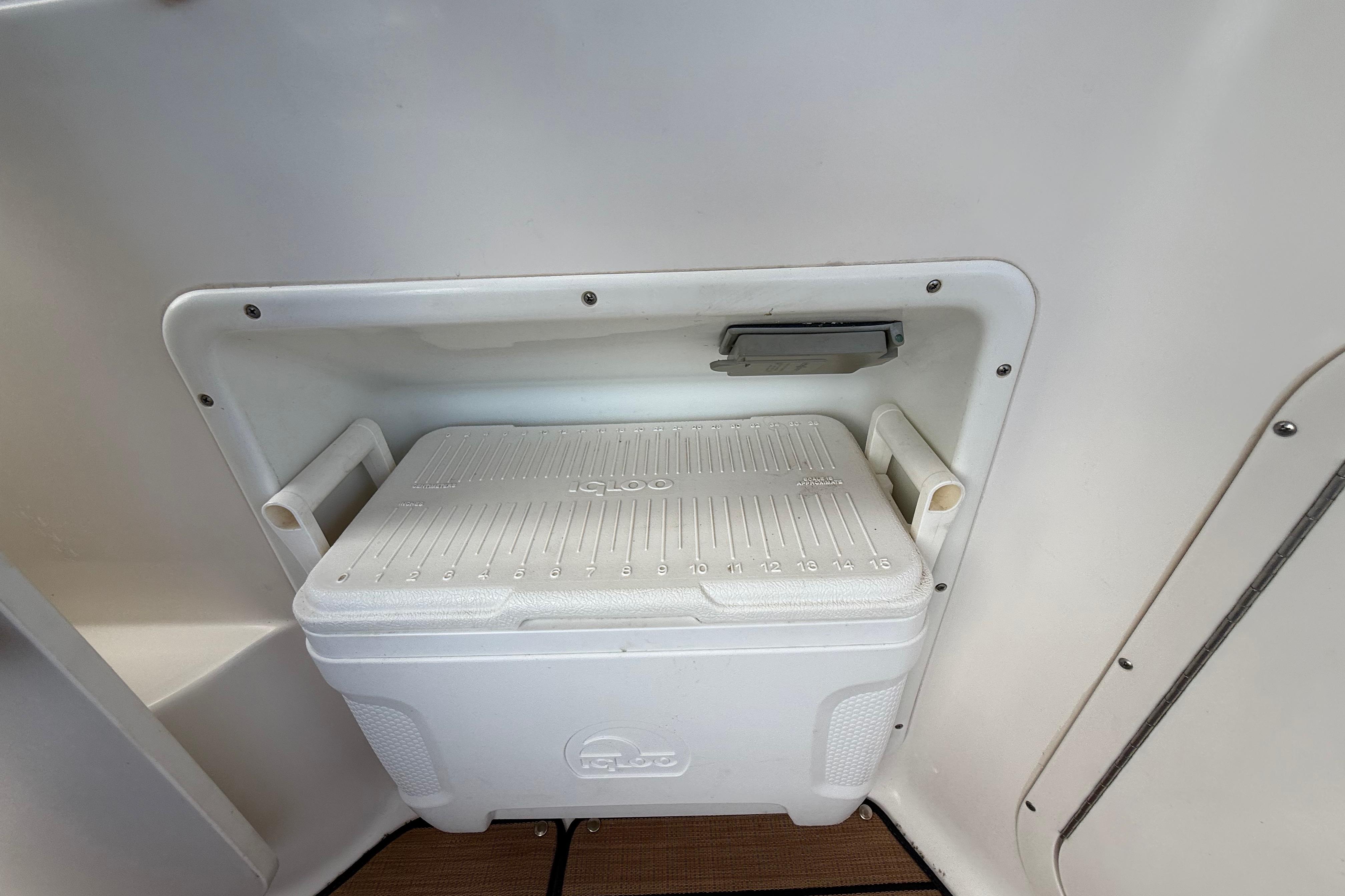 White Igloo cooler stored in a compartment on a 1999 Chaparral Signature 300 boat.