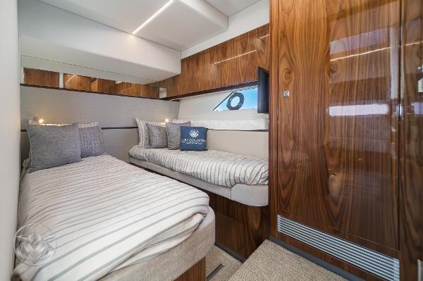 Luxurious cabin interior of 2025 Riviera 645 SUV yacht with twin beds and wooden finishes.