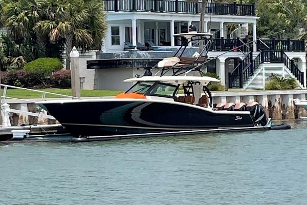 2020 Scout 420 LXF boat docked by waterfront home, surrounded by lush greenery.