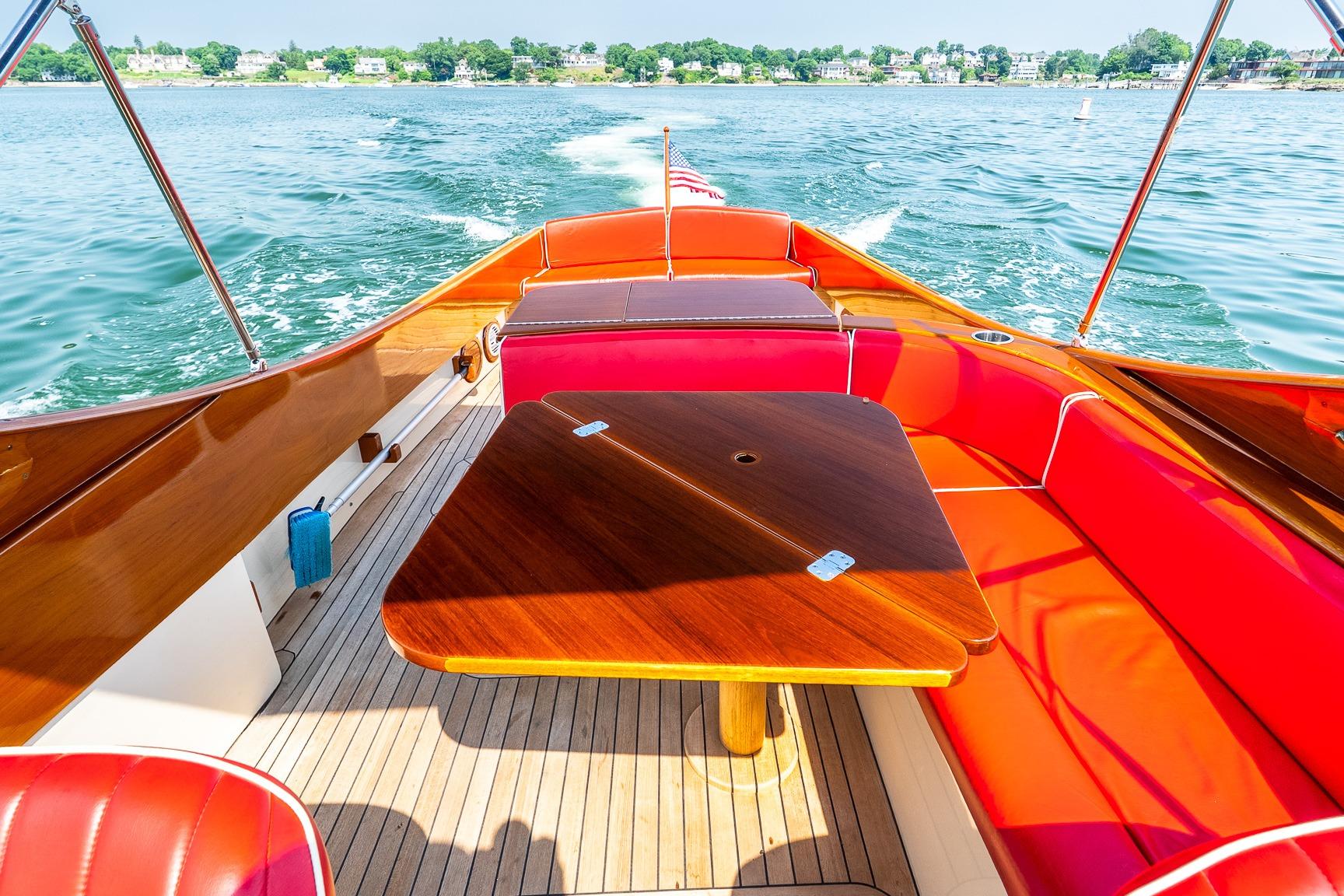 Hinckley Talaria 29R 2005 boat interior with red seating and wooden table on water.