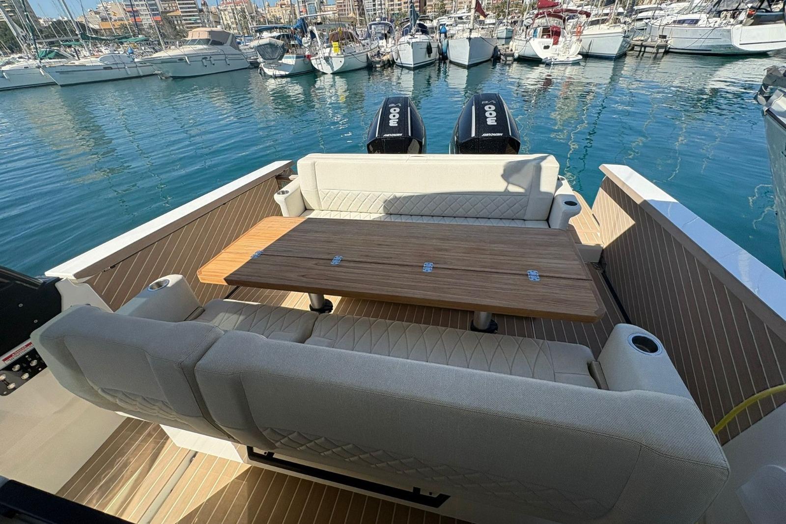2024 Saxdor 320 GTO boat interior with seating and table, docked in a marina.