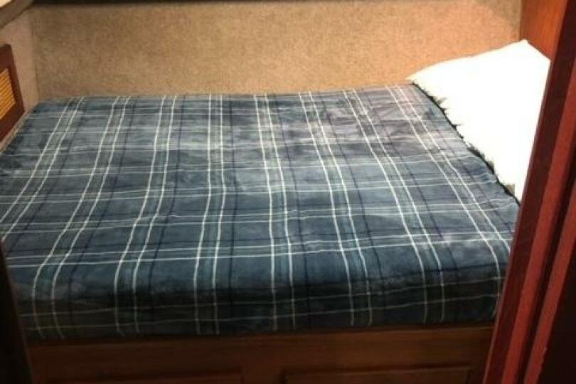 Cozy cabin bed in 1985 Bayliner 4550 Motoryacht with plaid bedding.