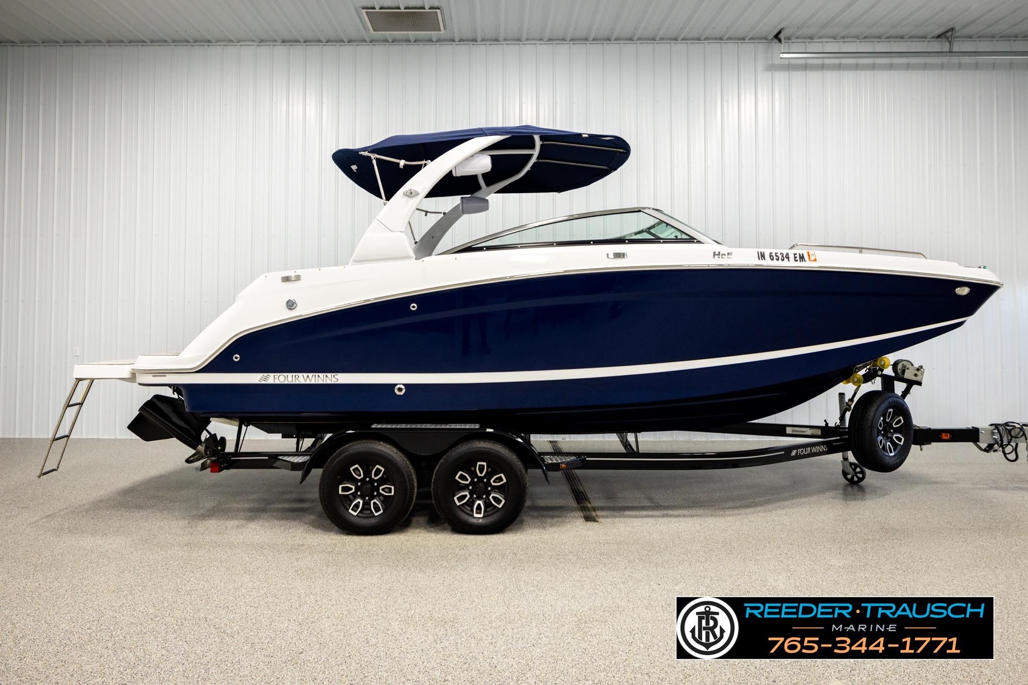 2024 FOURWINNS HD5 Surf boat on trailer in indoor showroom.