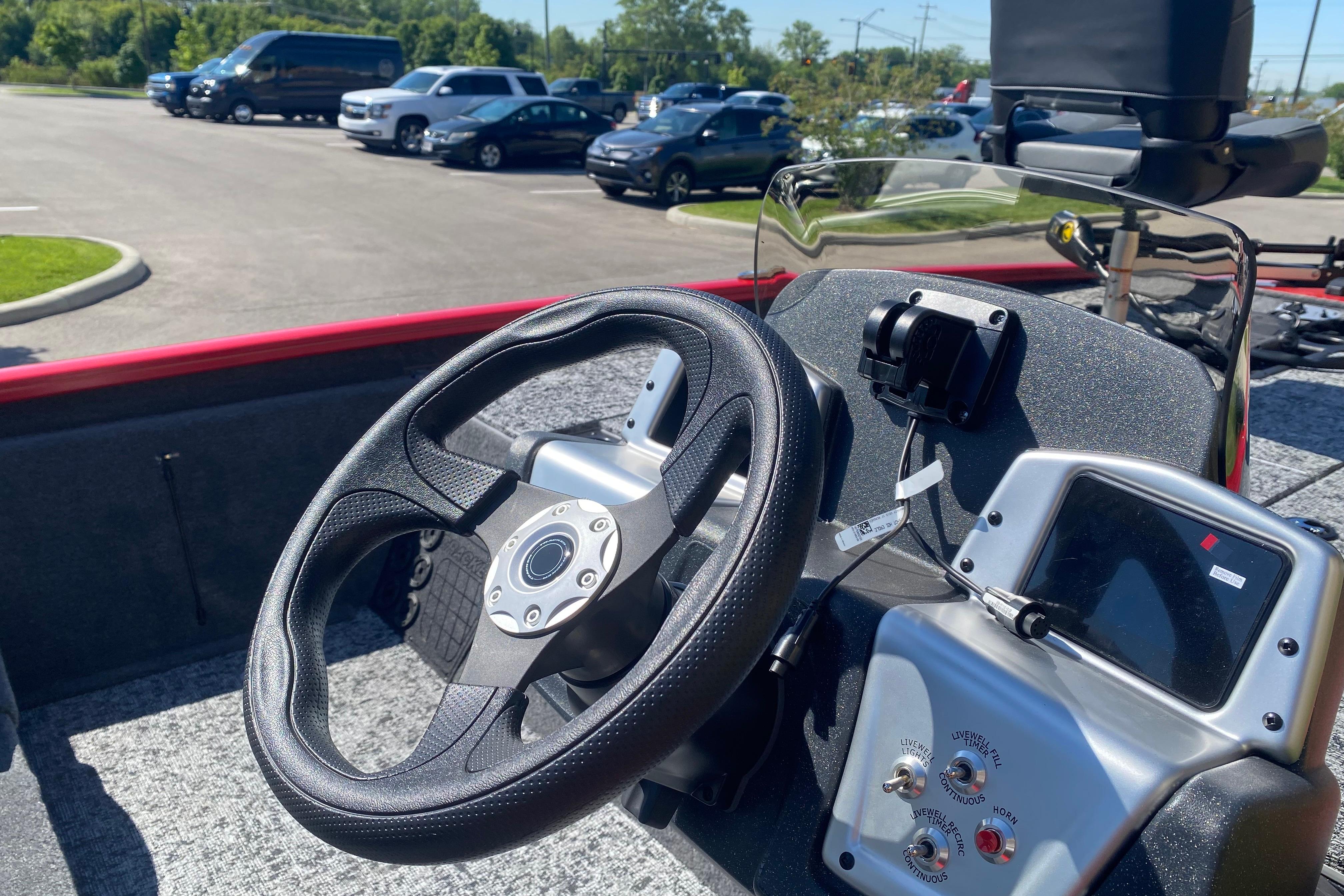 Steering wheel and dashboard of 2026 Tracker Pro Team 195 boat in parking lot.