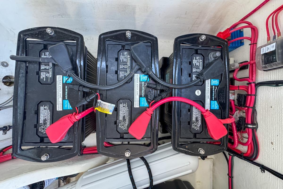 Three marine batteries in a 2022 Velocity 290sc boat, connected with red and black cables.