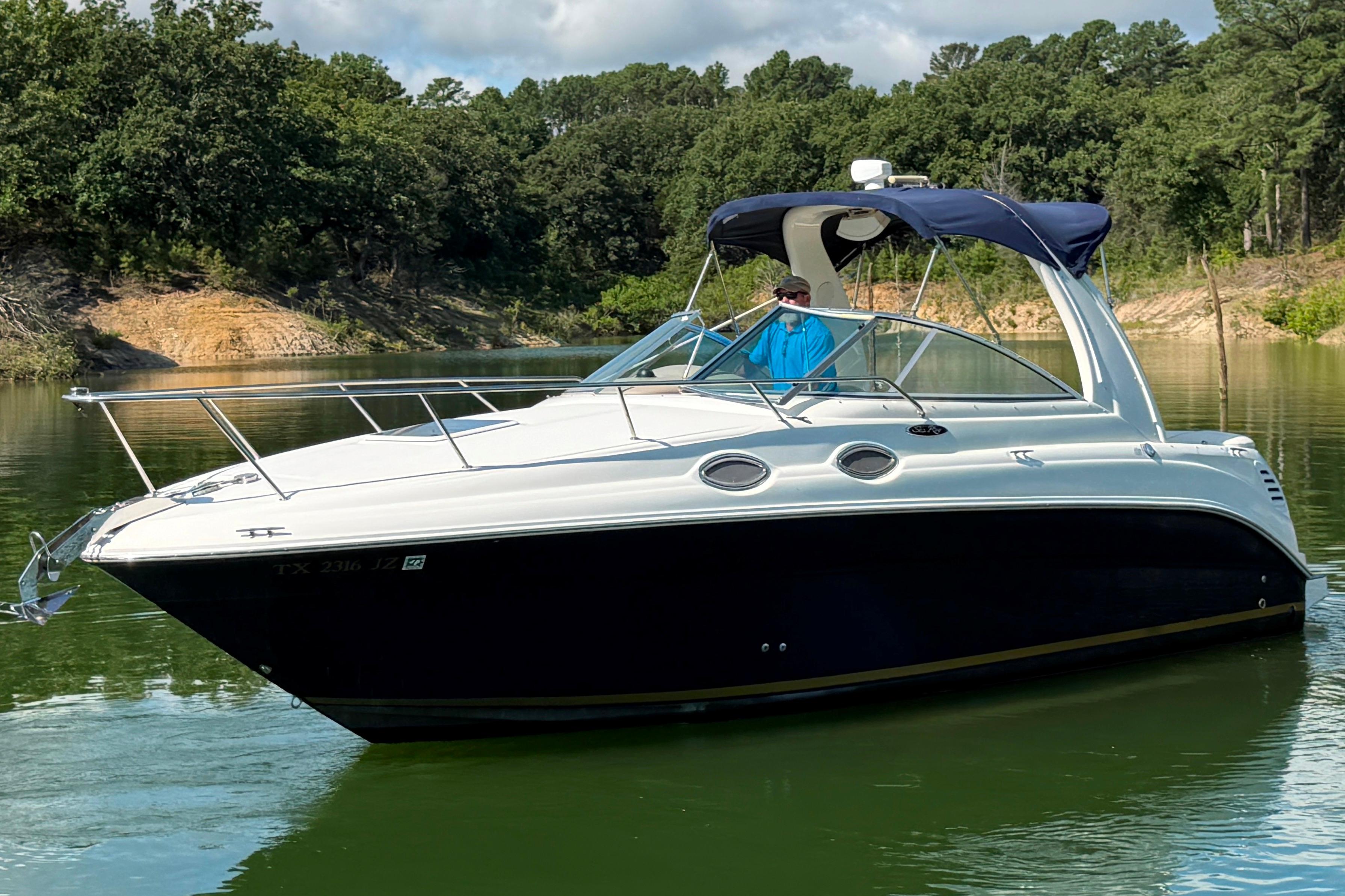 2004 Sea Ray Sundancer 260 cruising on a serene lake with lush forest backdrop.