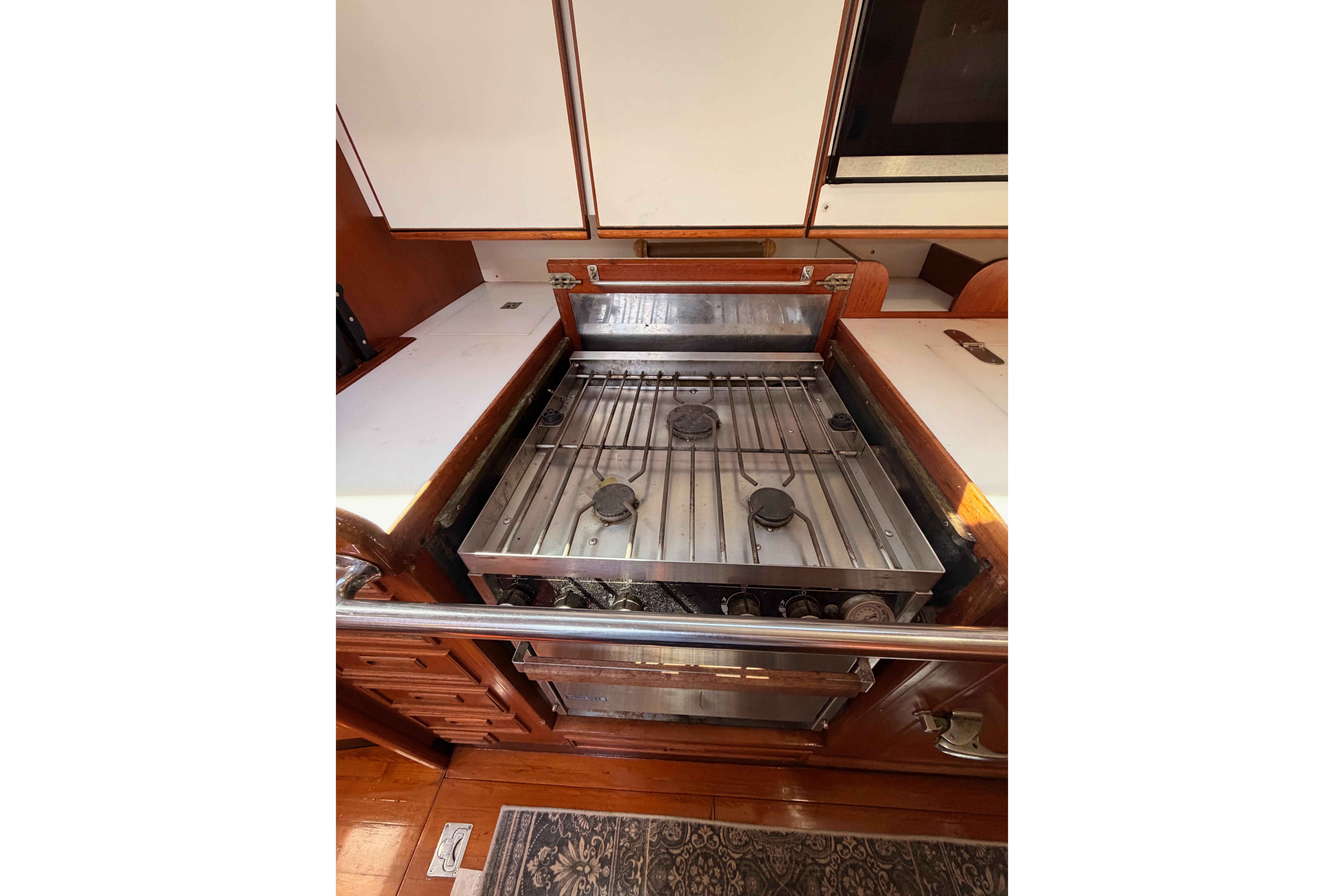 Stainless steel stove in a 1991 Hylas 51 yacht kitchen, featuring wooden cabinetry.