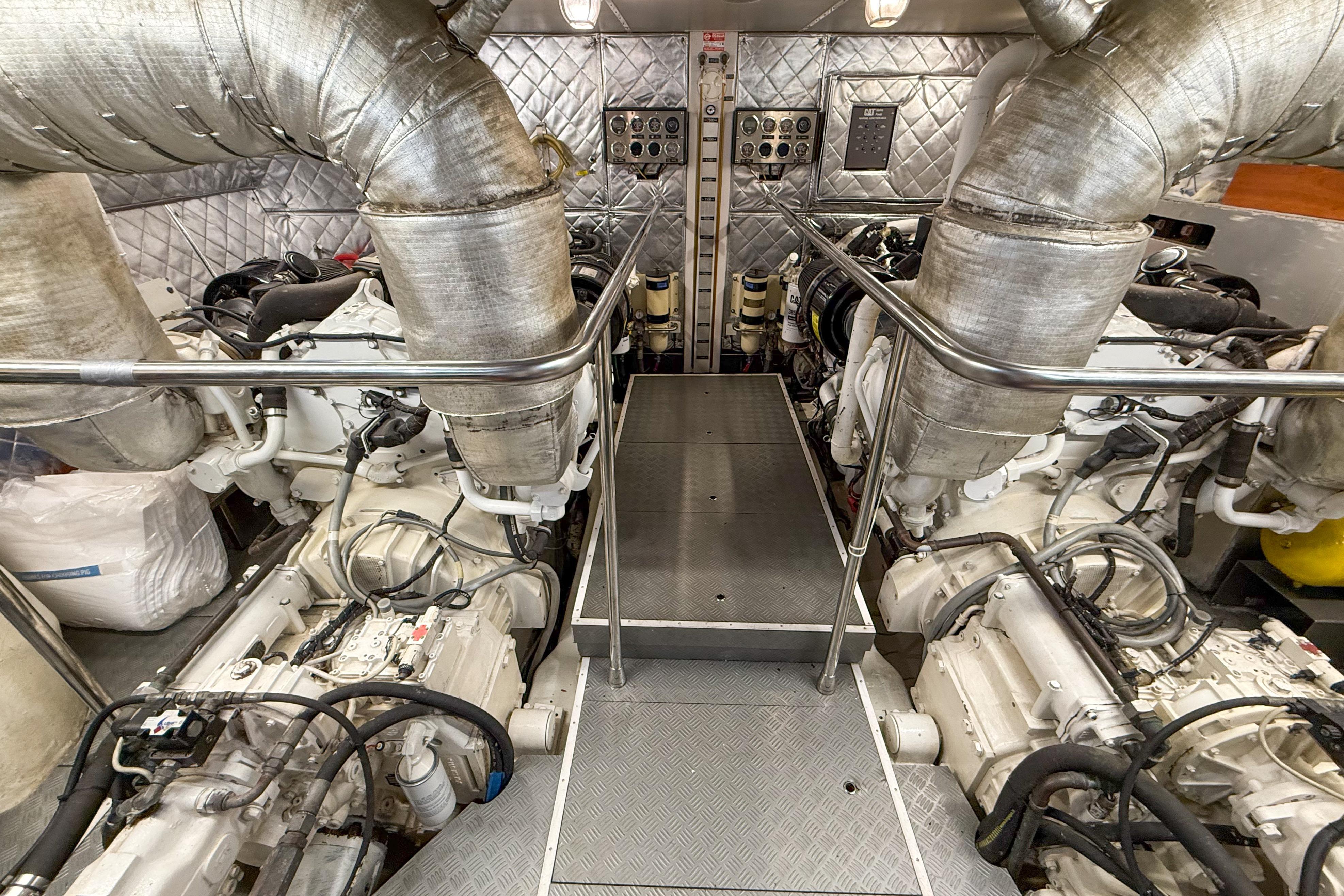 Engine room of a 2007 Canados 86 yacht, featuring dual engines and metallic piping.
