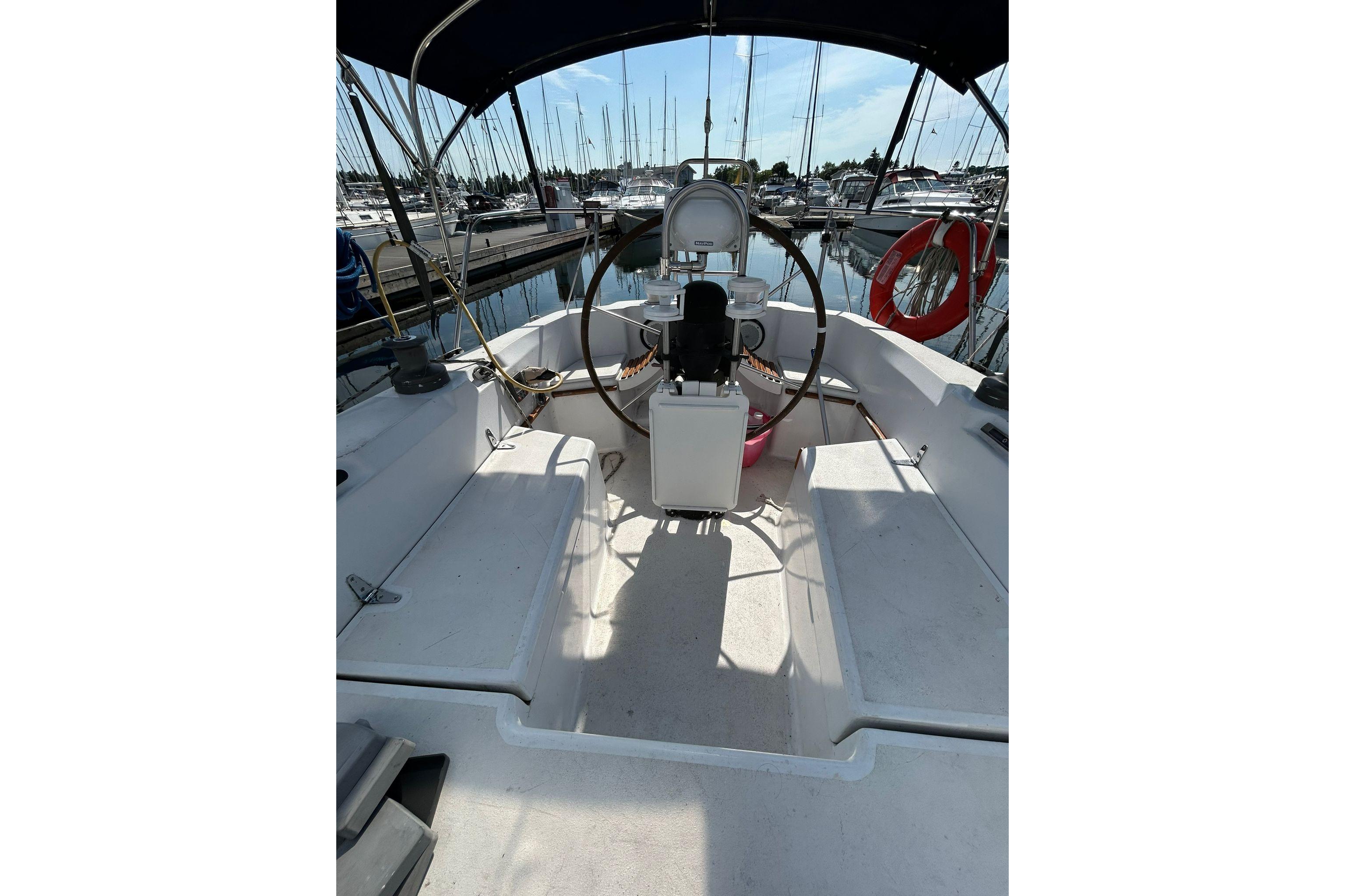 Cockpit of 1984 C&C 34 sailboat with steering wheel and marina view.