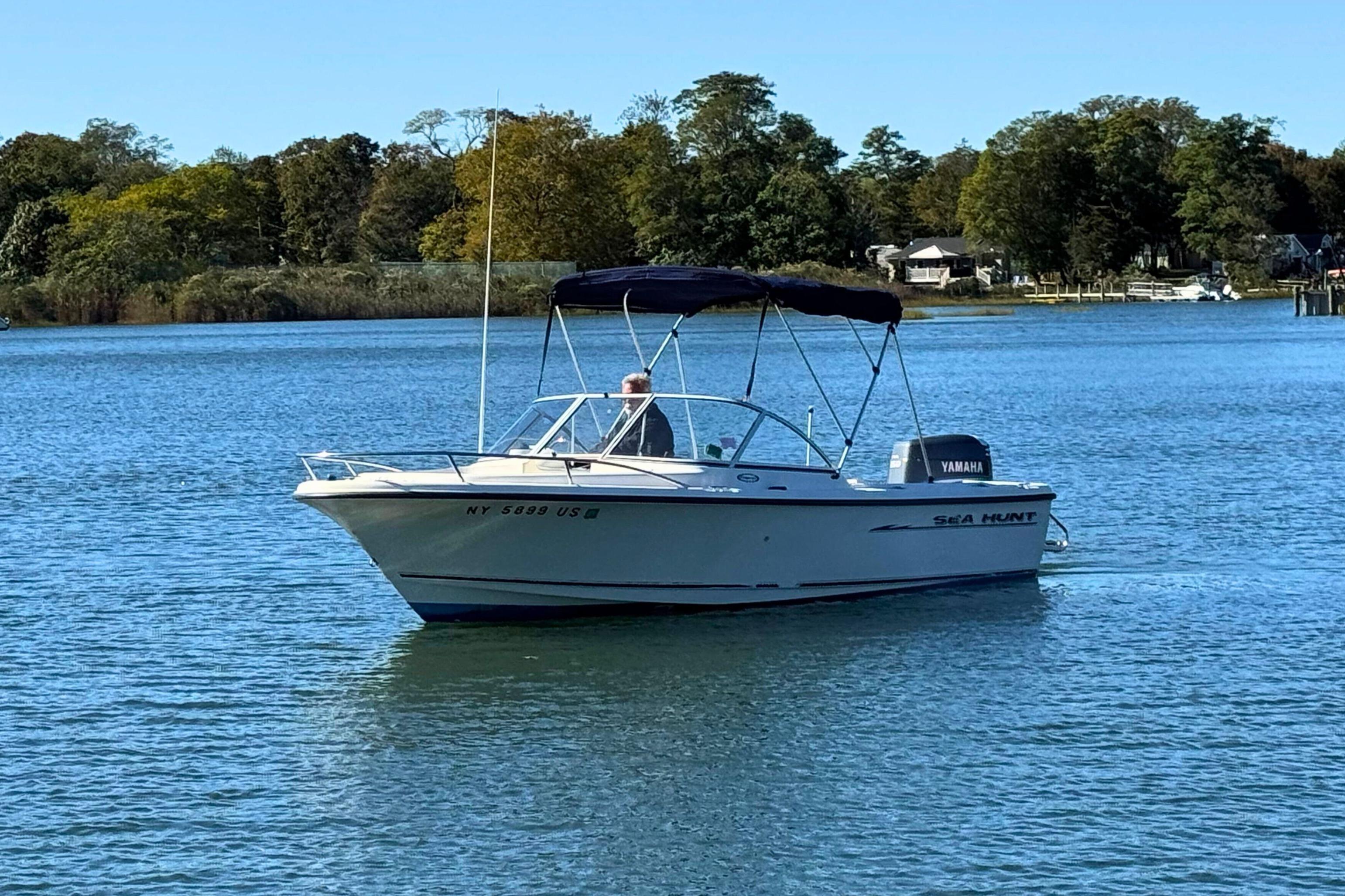 2002 Sea Hunt Escape 200 boat on calm water, surrounded by trees and houses.