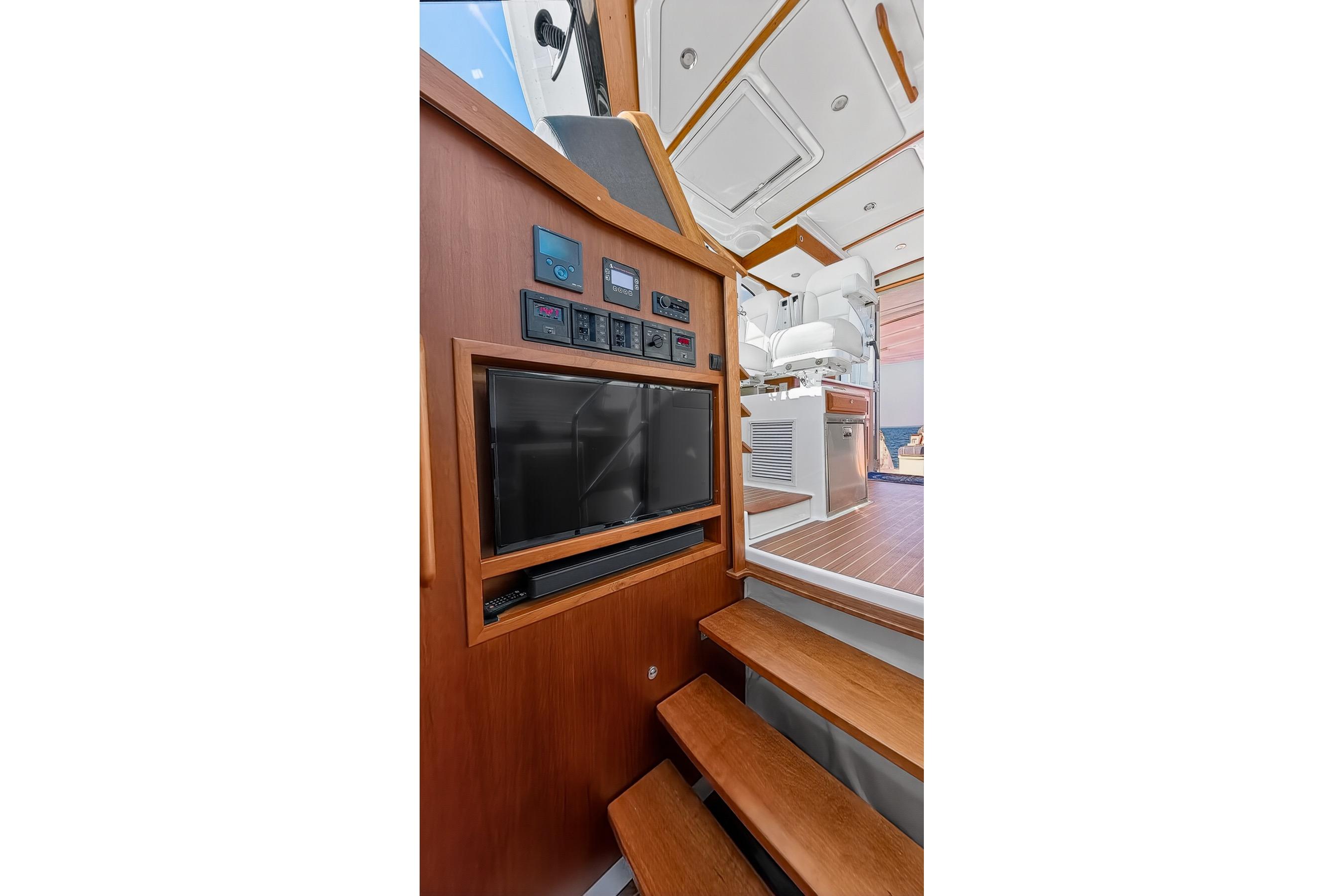 2024 Back Cove 39O yacht interior with wooden stairs, control panel, and seating area.