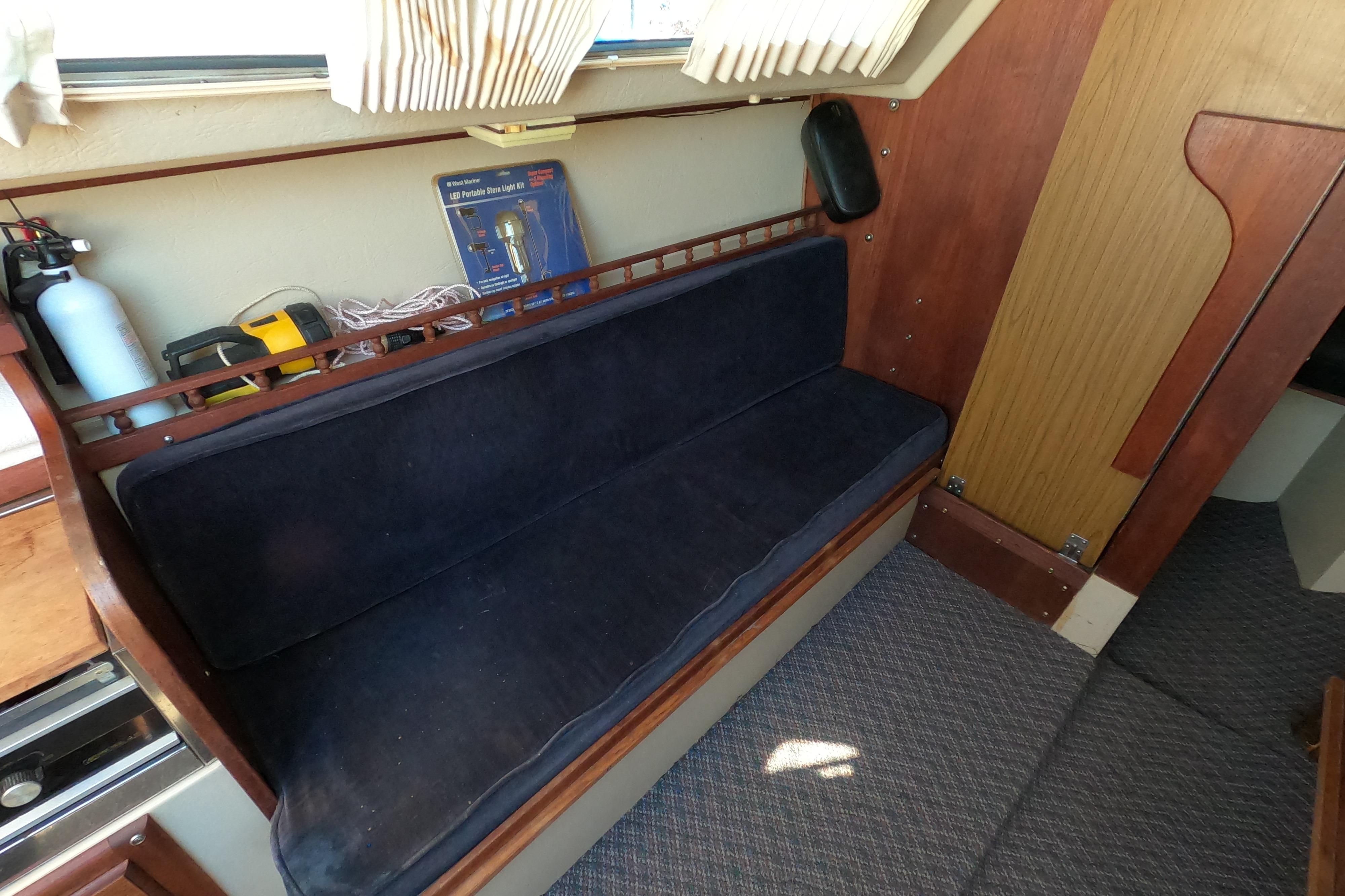 Interior of a 1983 Catalina 25 sailboat with a blue cushioned bench.