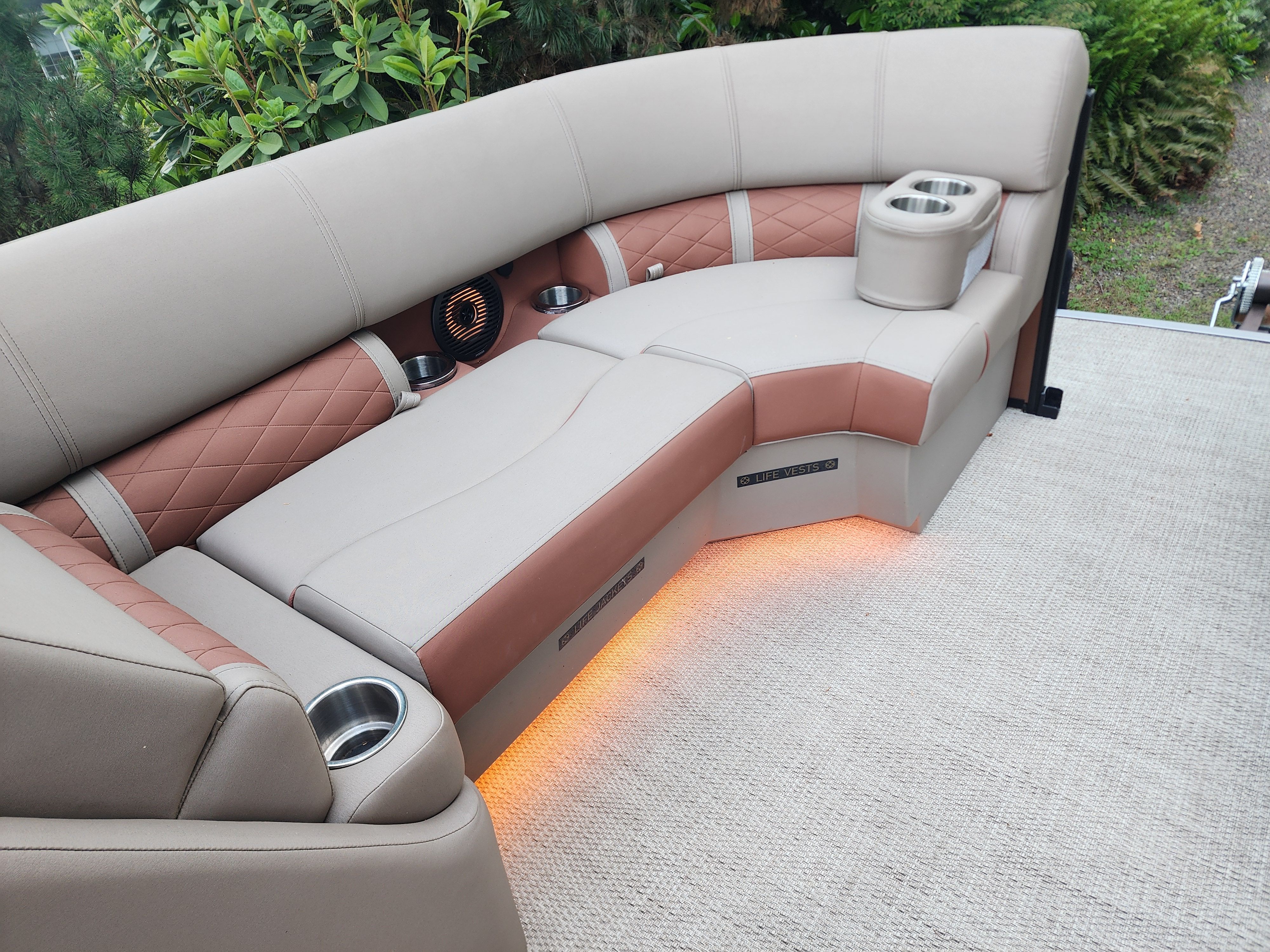 The image shows a luxurious boat seat with beige and brown upholstery and LED lighting.