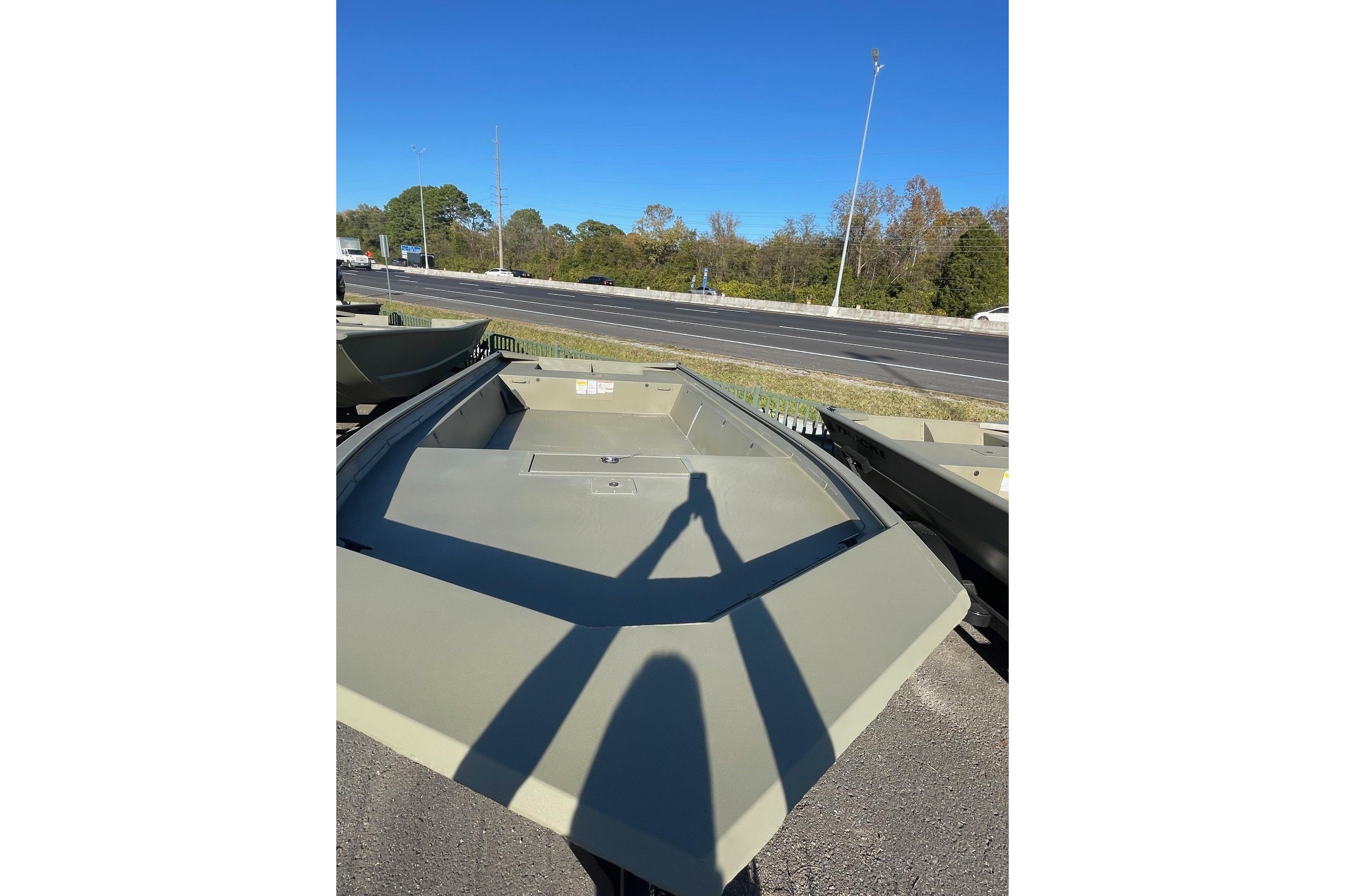 2025 Tracker Grizzly 1860 Utility boat on display near a highway.