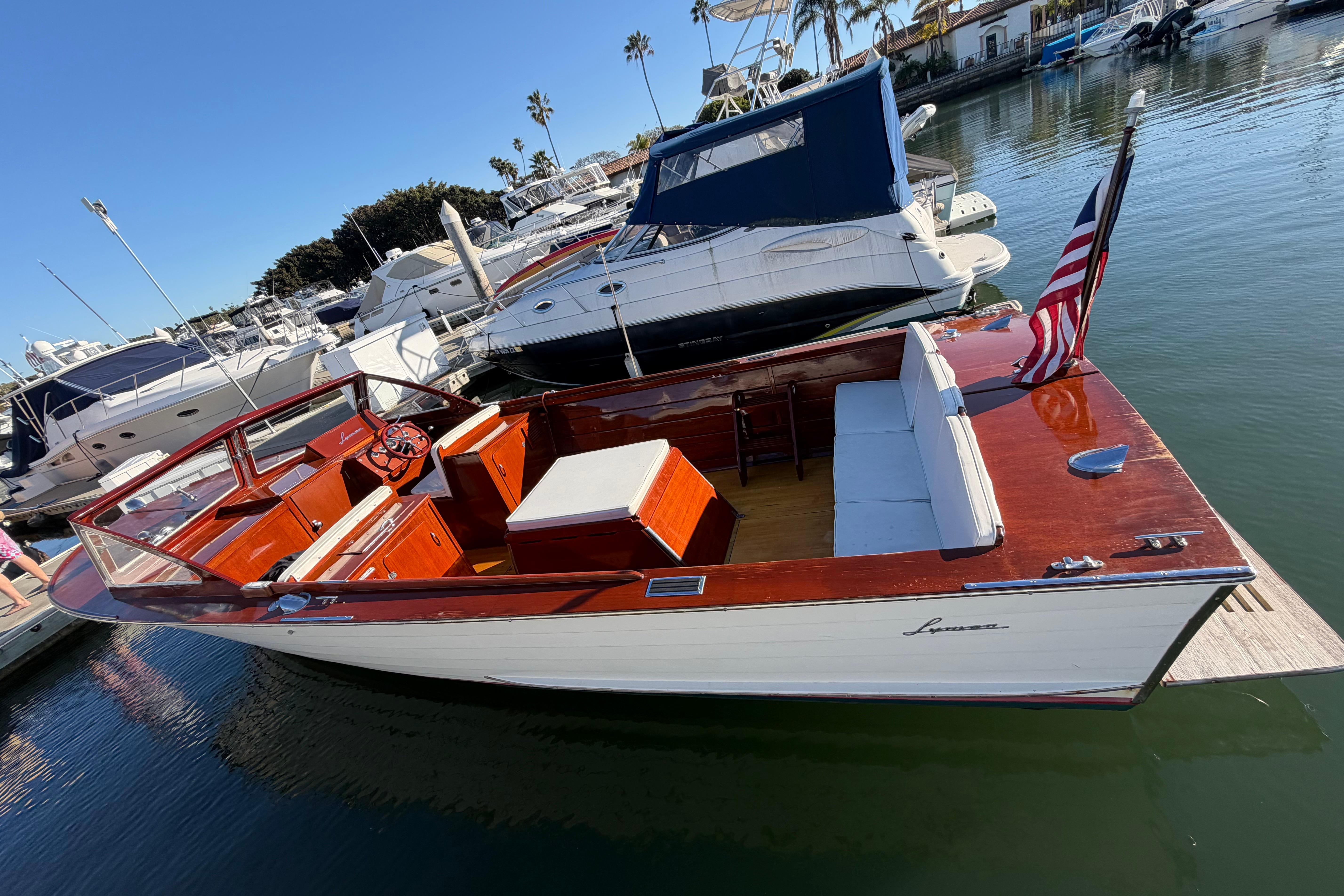 1964 Lyman 25 Sleeper boat docked, featuring classic wooden design and American flag.