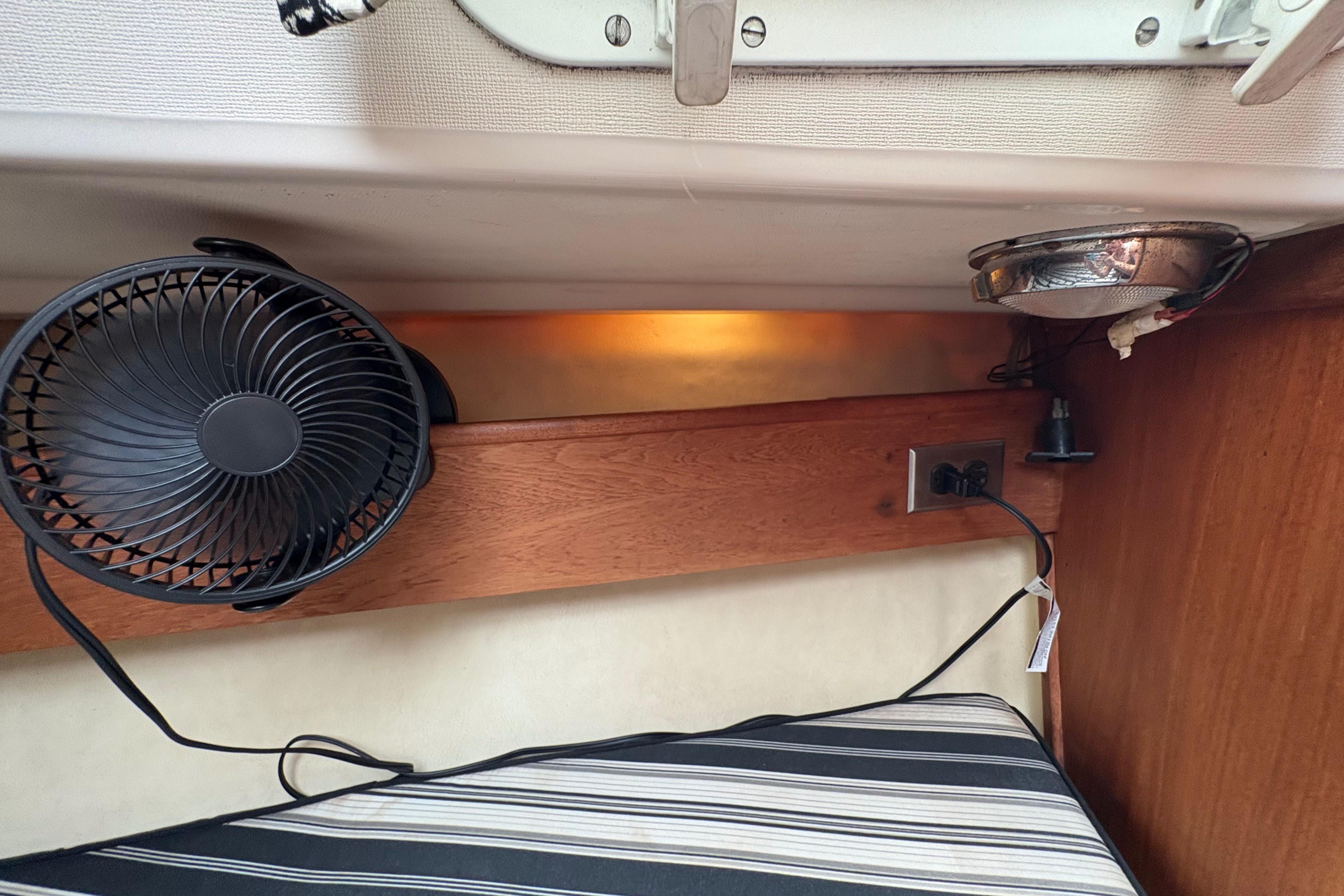 1981 Sabre 31 interior with fan, striped cushion, and electrical outlet.